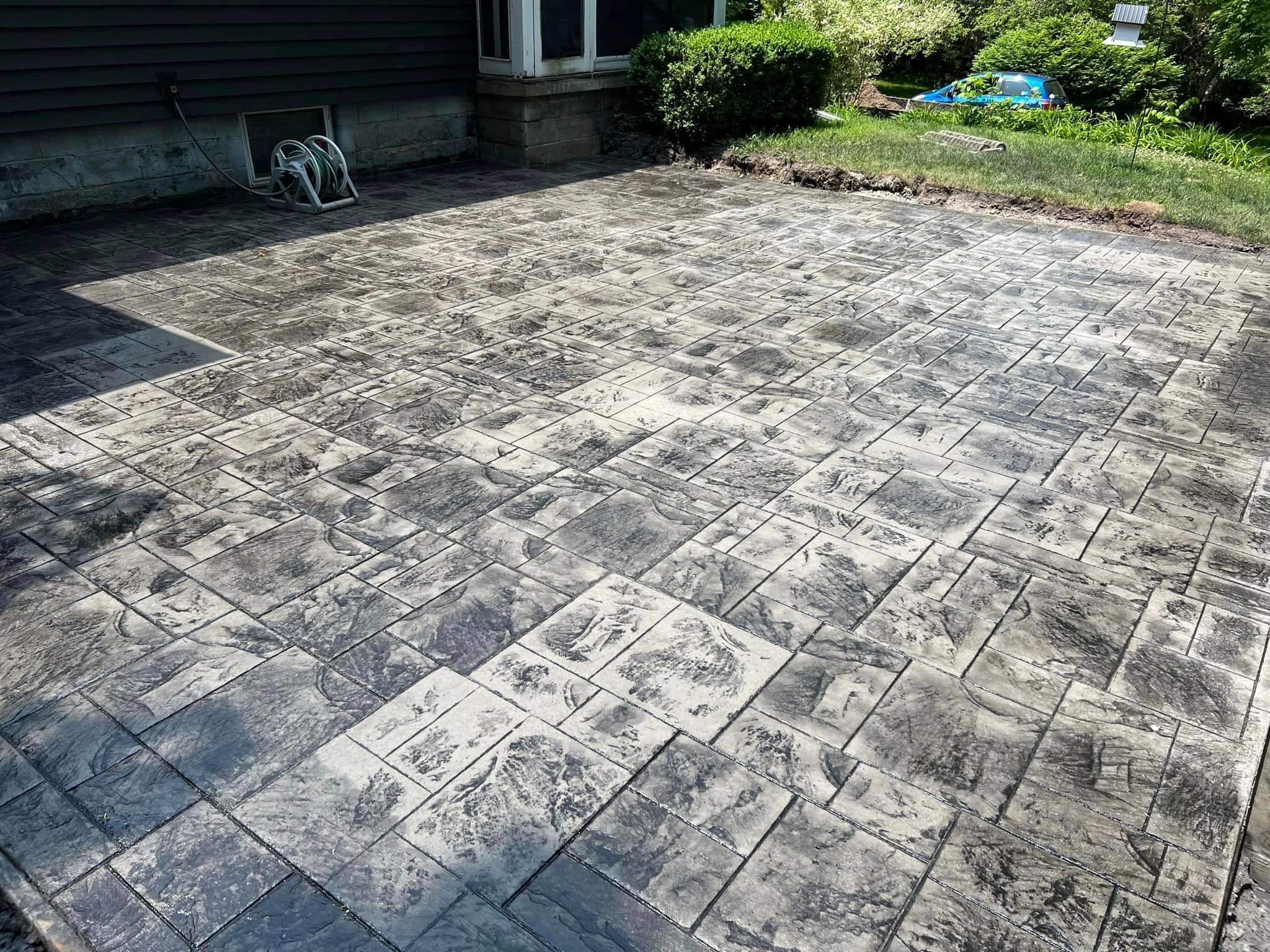 Large stamped concrete patio with textured stone pattern in residential backyard