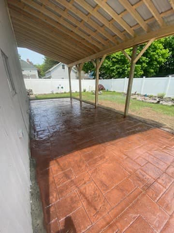 Stamped concrete patio under covered porch with white privacy fence