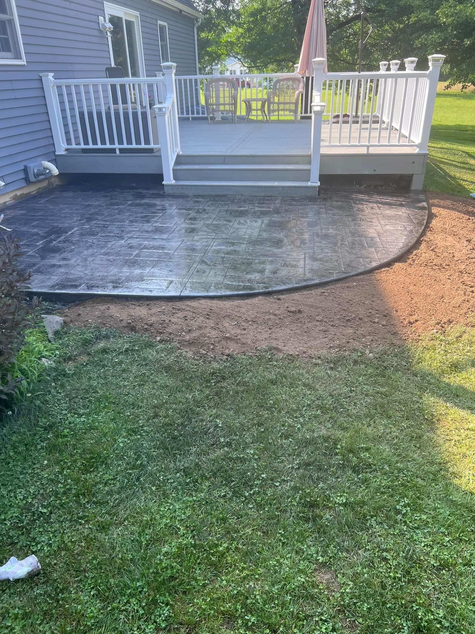 Stamped concrete patio with curved edge extending from white deck with stairs