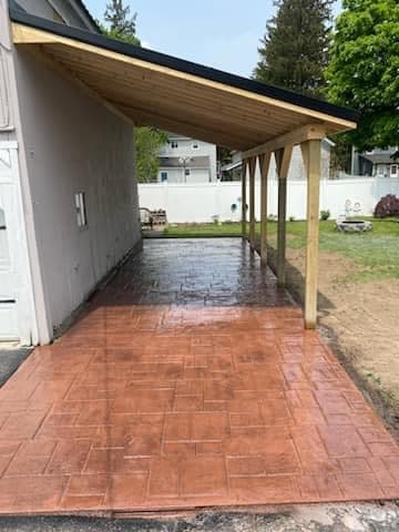 Completed stamped concrete patio in herringbone pattern under wooden pergola