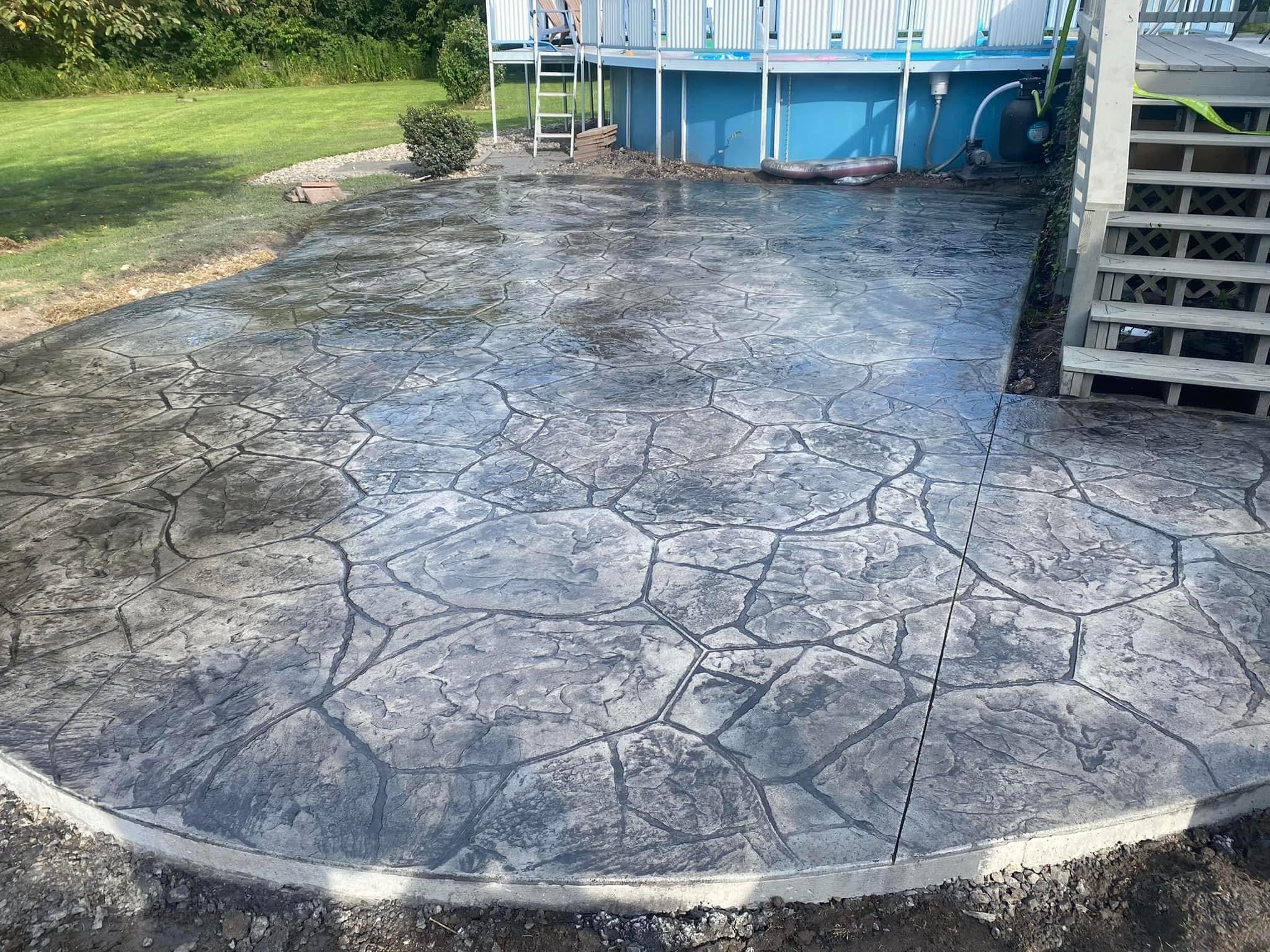 Stamped concrete patio with flagstone pattern next to above-ground pool