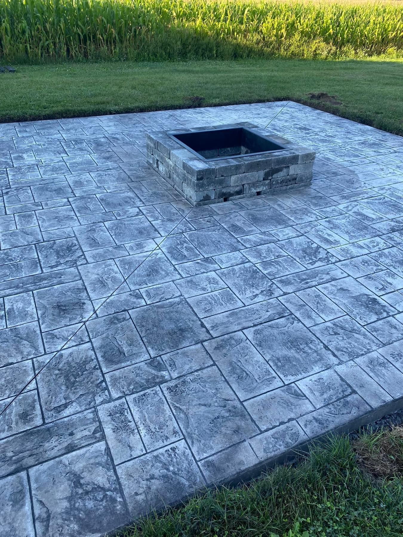 Stamped concrete patio with herringbone pattern and square stone fire pit