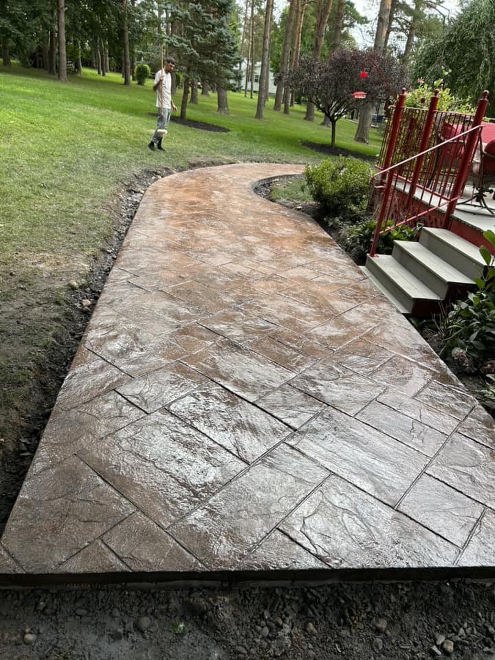 Curved stamped concrete walkway with red metal railing and steps