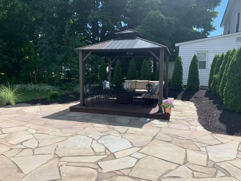 Natural stone patio with gazebo and outdoor furniture in backyard