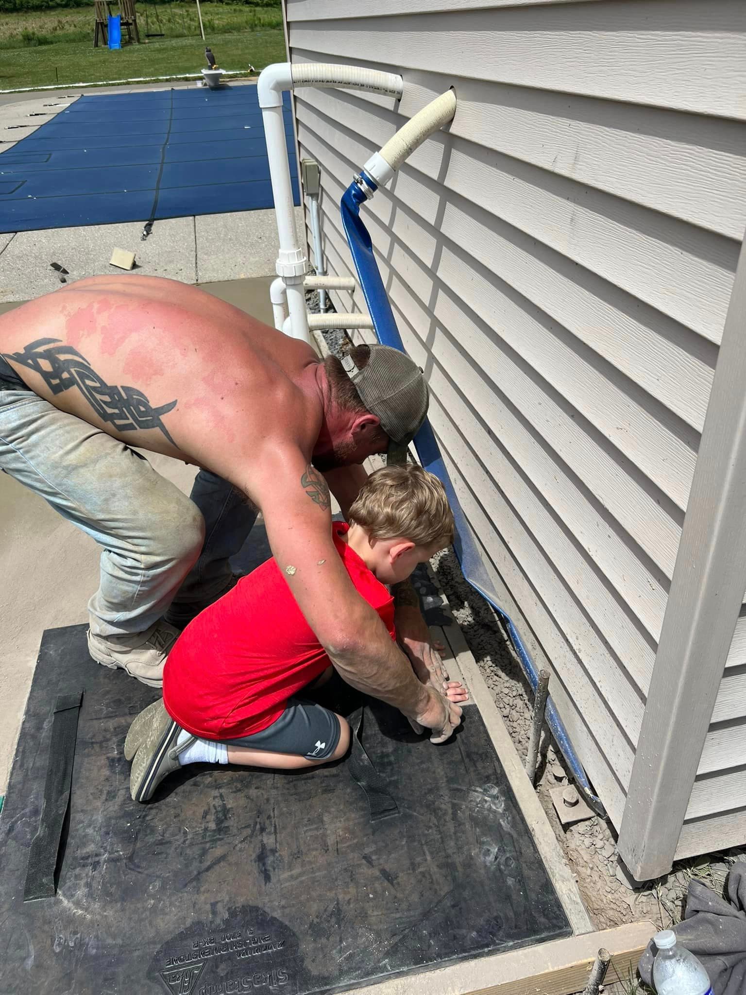 Two workers applying waterproofing membrane to house foundation