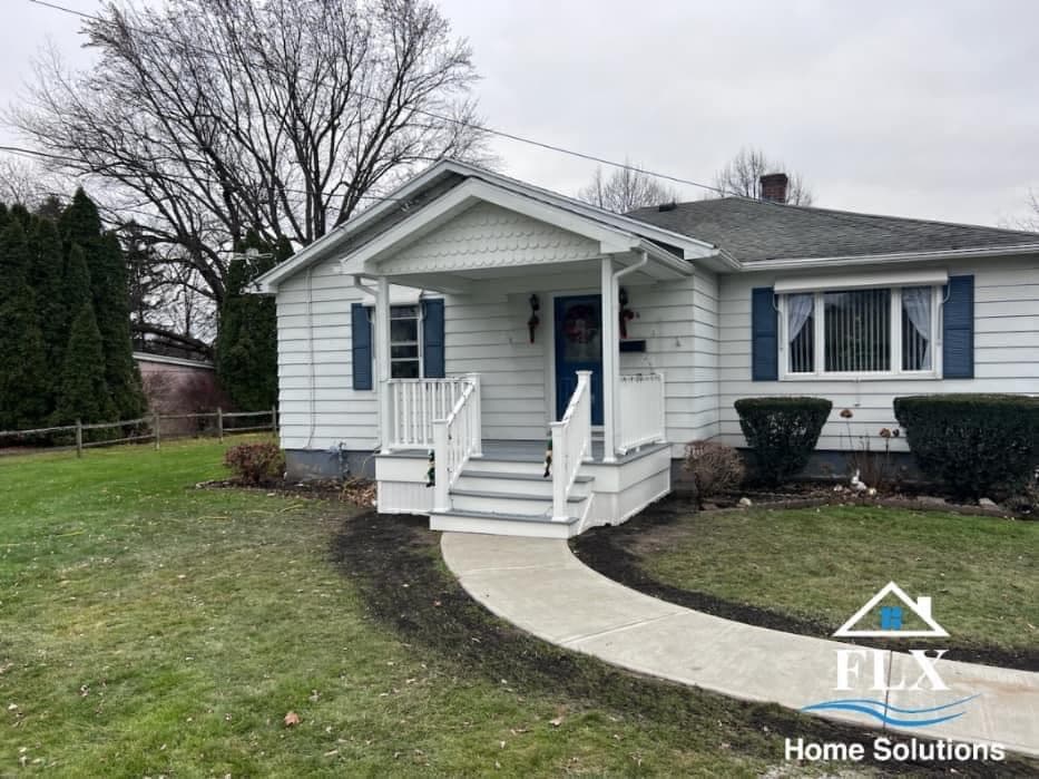 White ranch house with blue shutters and curved concrete sidewalk leading to front porch