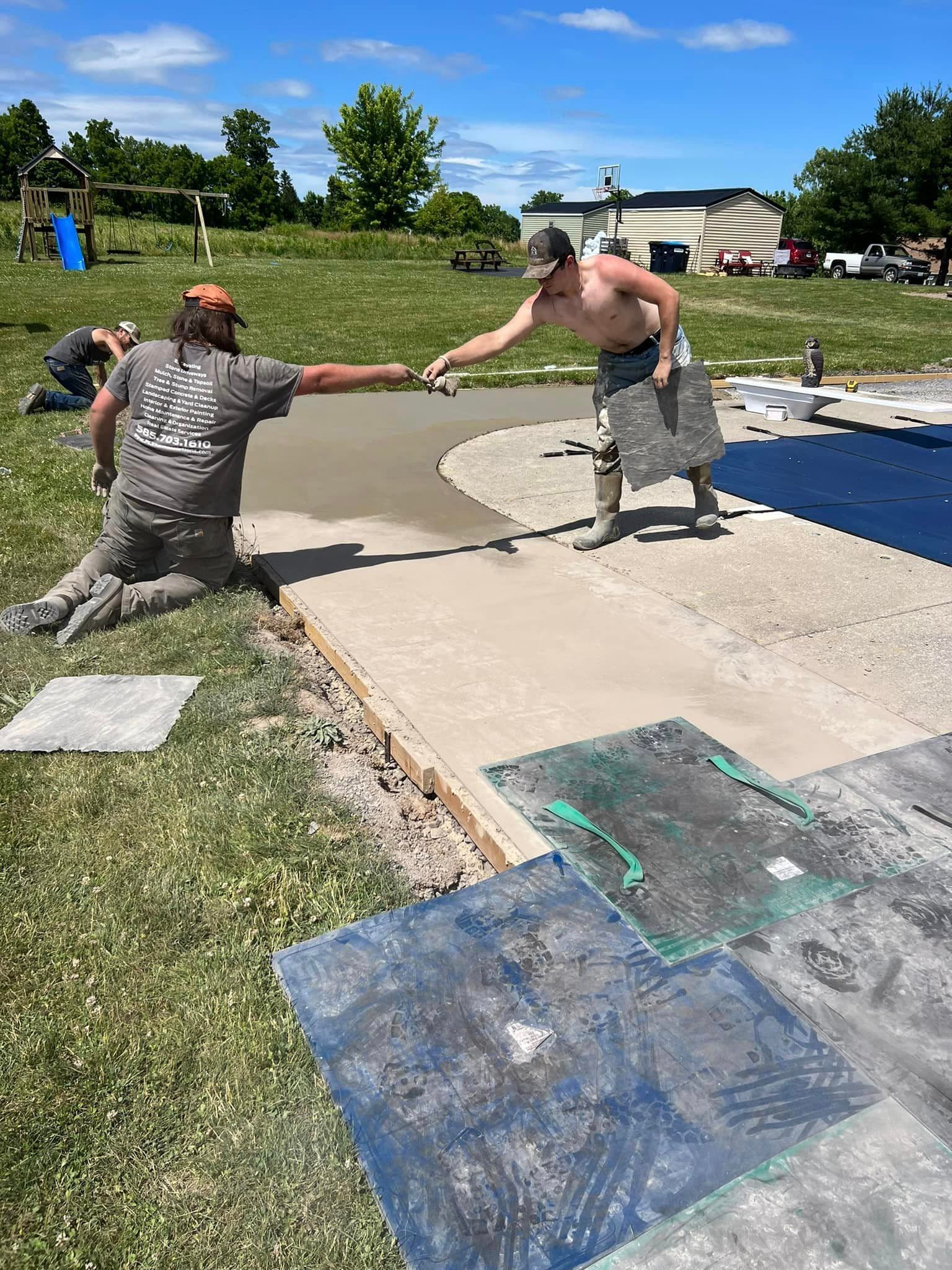 Two workers smoothing freshly poured concrete pad in residential backyard