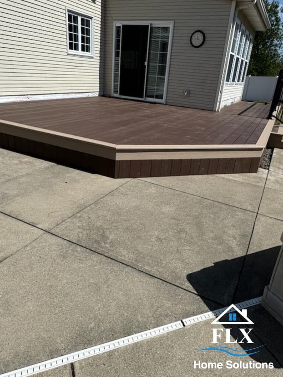 Composite deck with two-tone trim and adjoining concrete patio at residential home