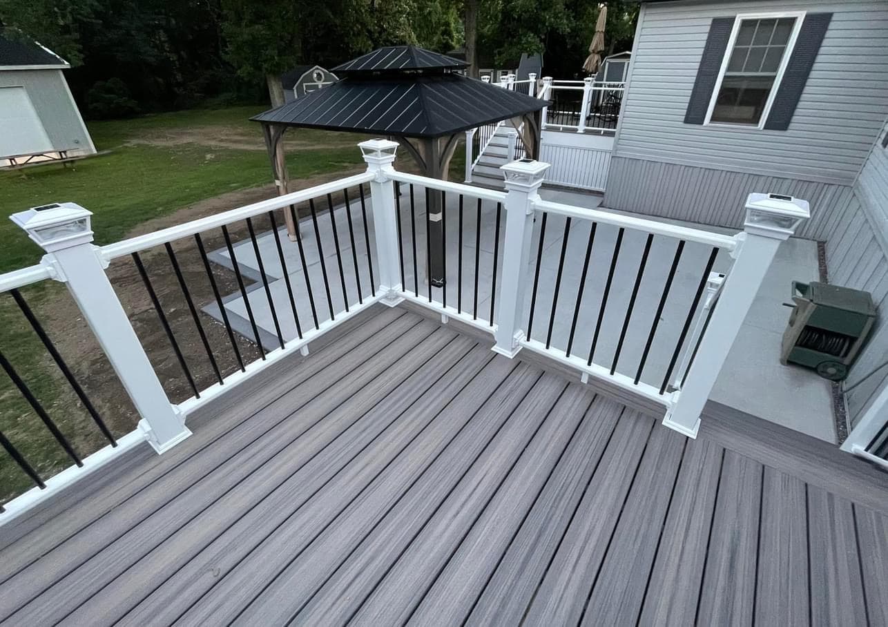 Composite deck with gray flooring, white posts, and black balusters