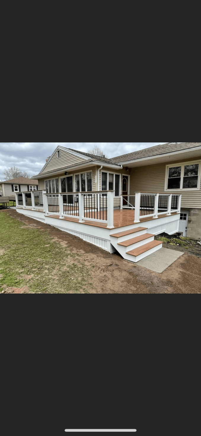 Custom composite deck with white railings and wood-tone stairs on ranch home