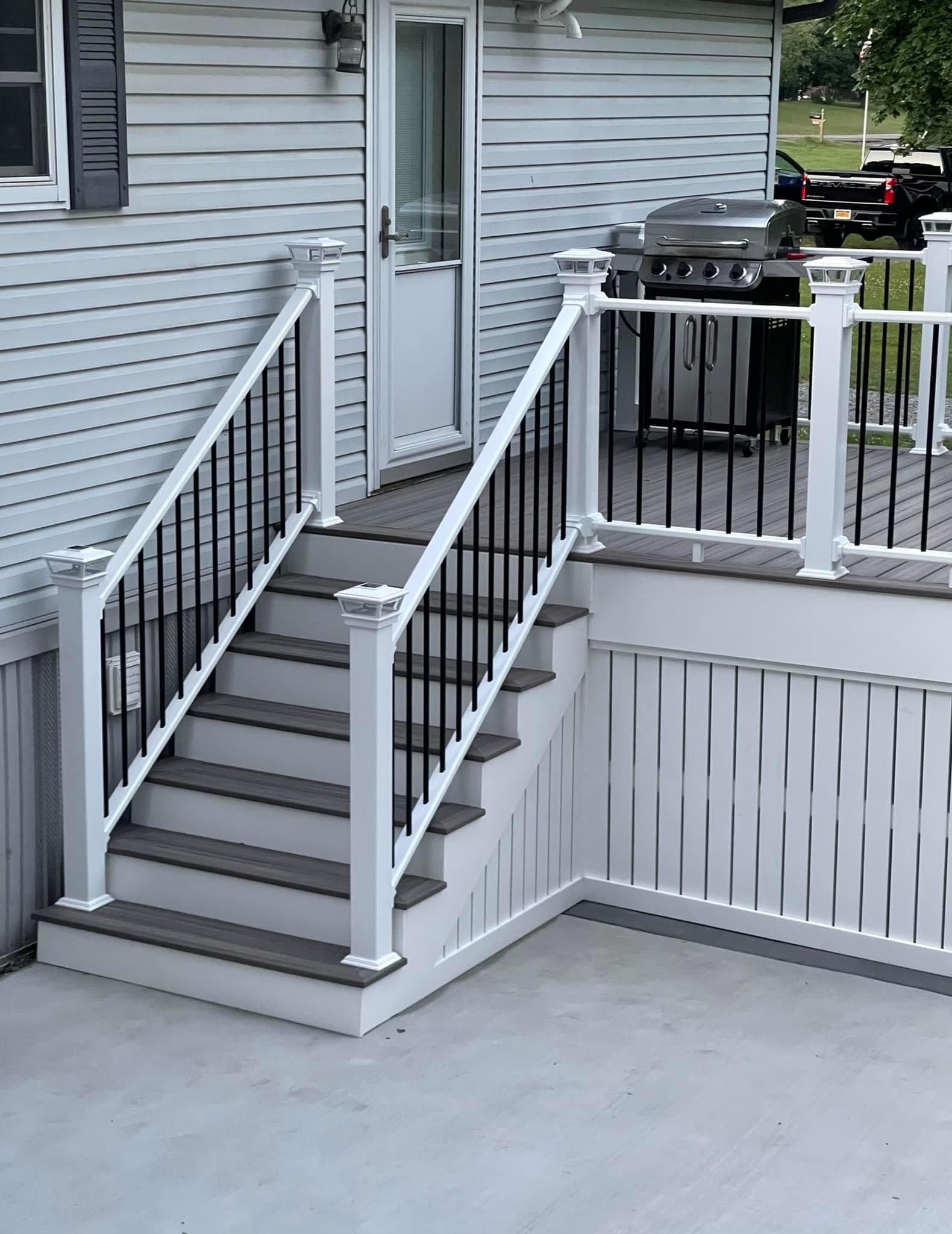 Gray composite deck with white posts, black metal balusters, and stairs