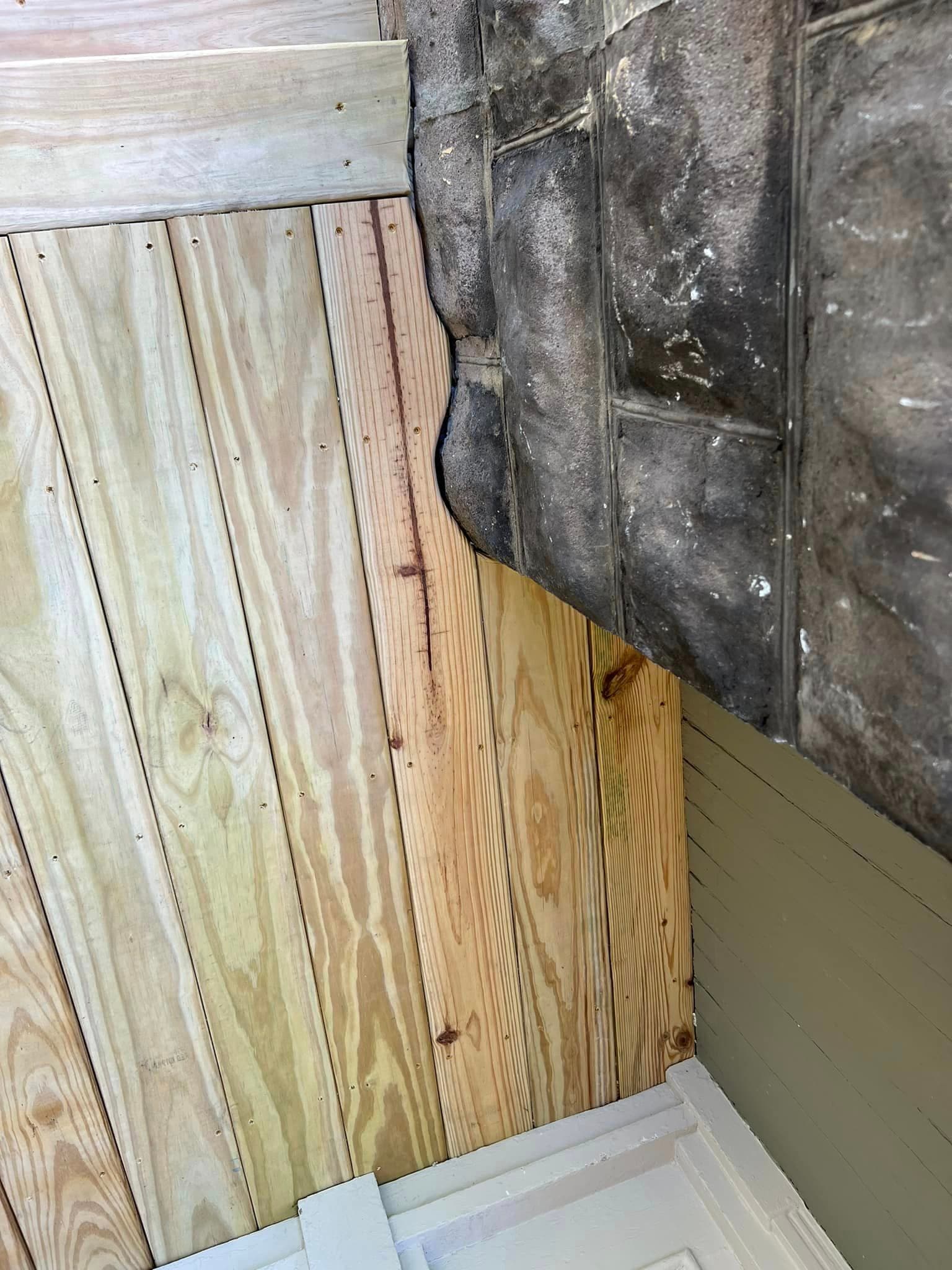 New wooden deck construction meeting weathered concrete foundation wall