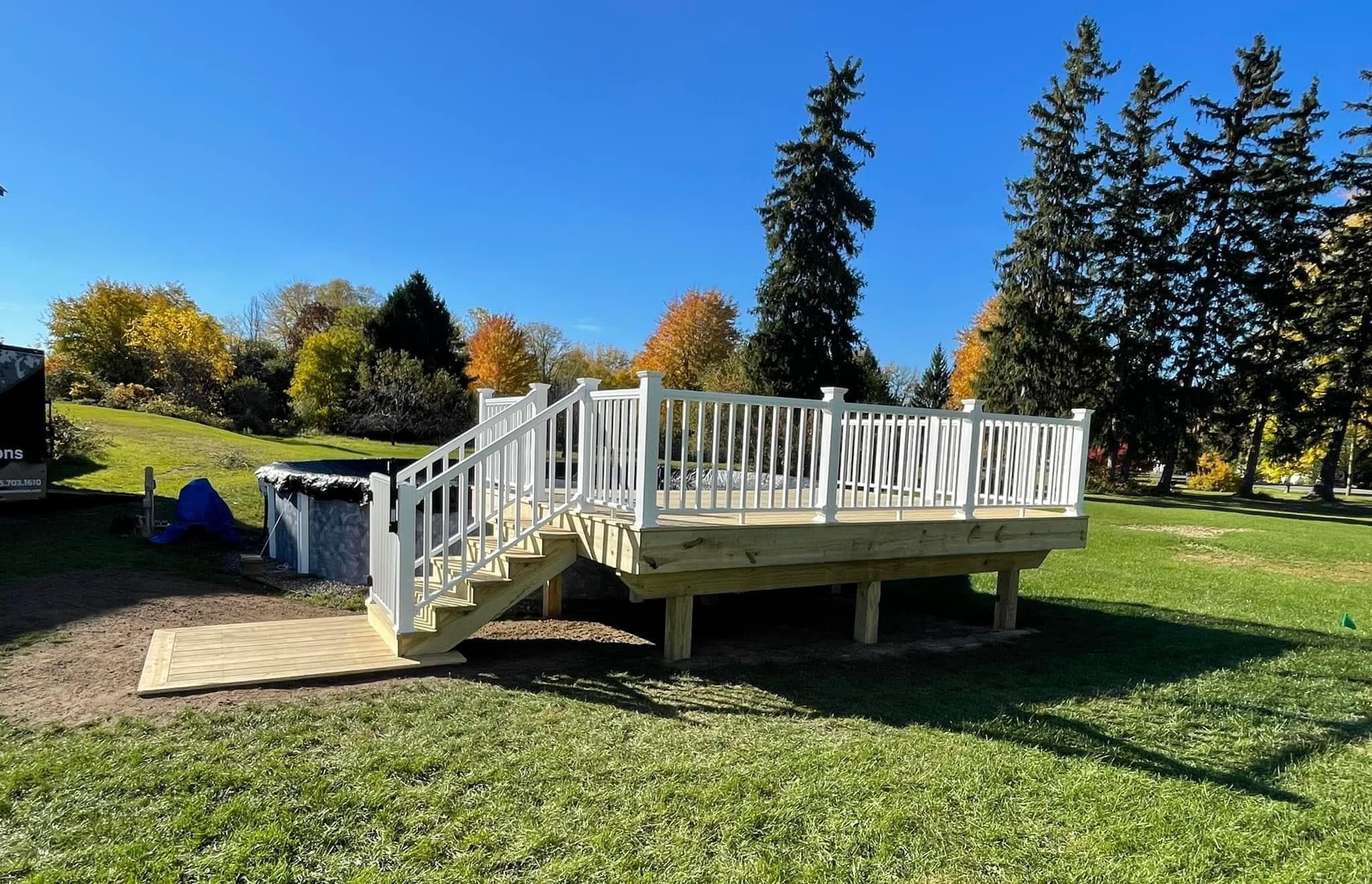 Newly constructed elevated deck with white railings and stairs in a park setting