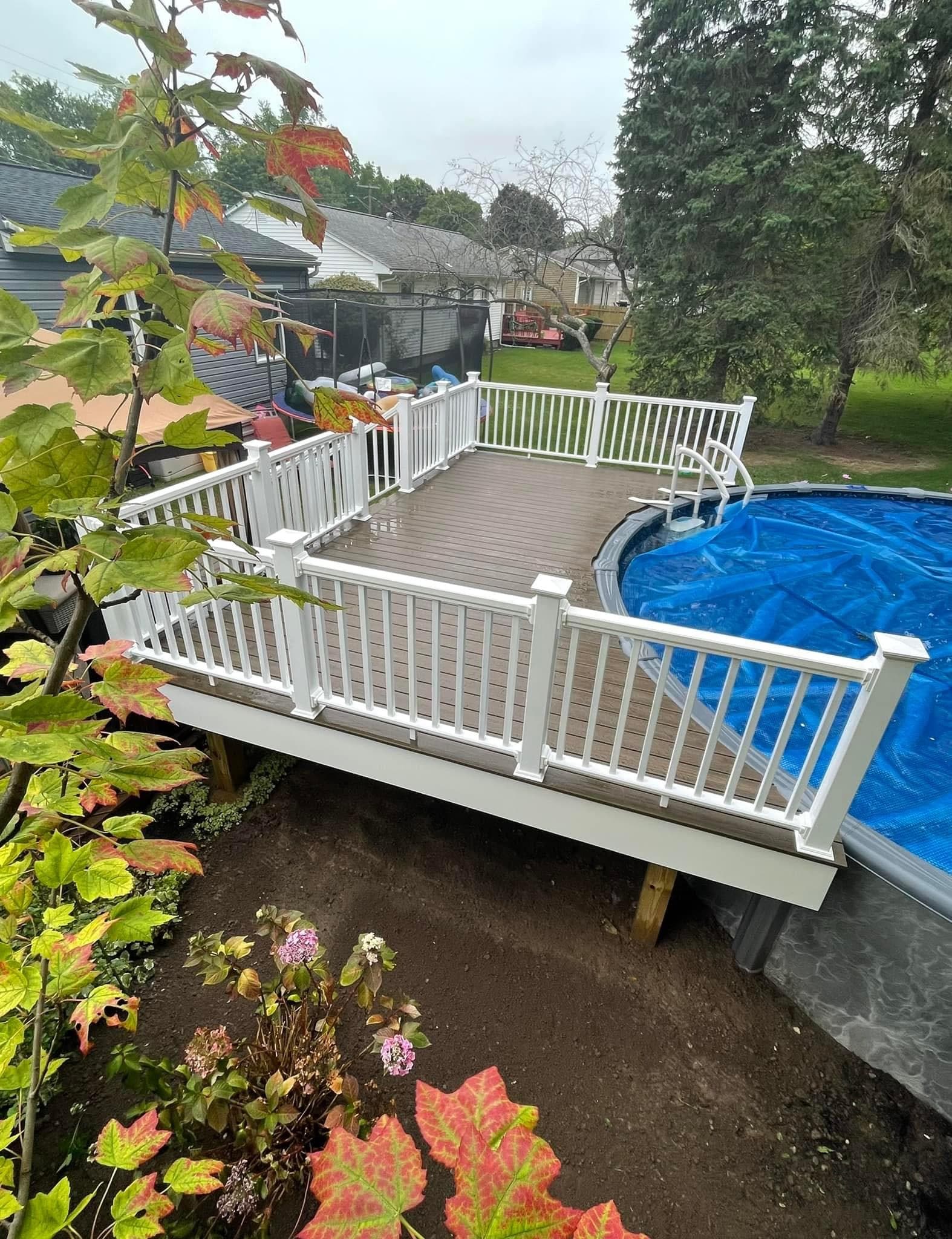 White composite deck with railing surrounding blue above-ground pool in backyard