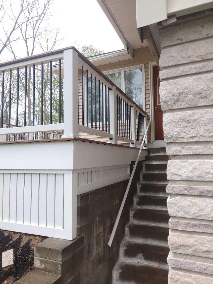 White elevated deck with black railings connecting to exterior stone staircase