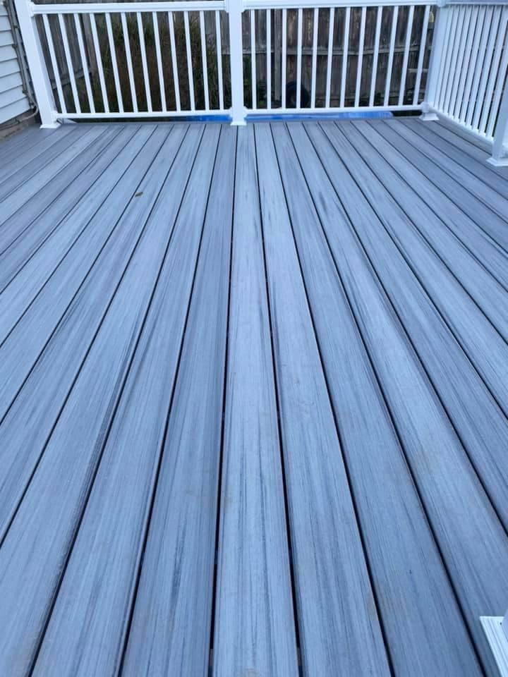 Newly installed gray composite deck with white railing and vertical balusters