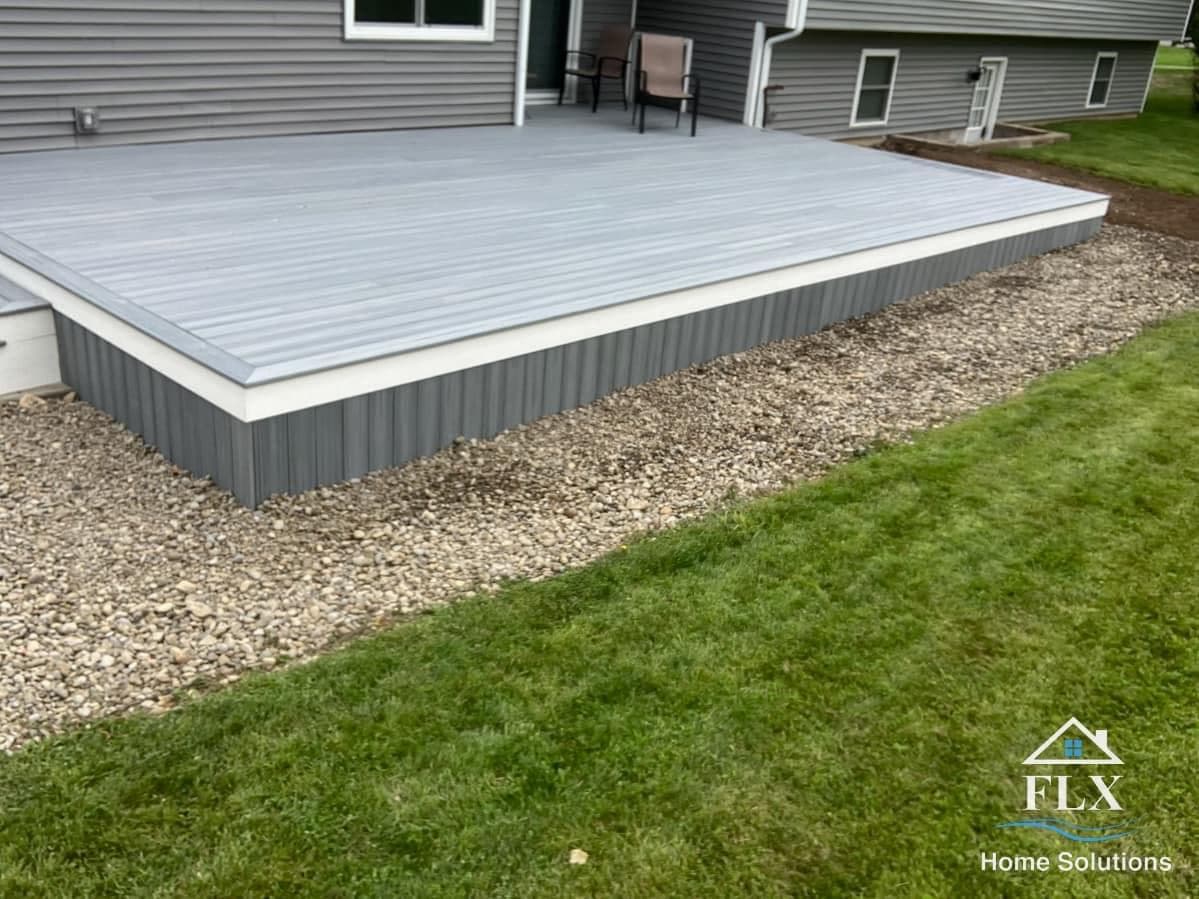 Elevated gray composite deck with white trim and matching skirting on gravel base
