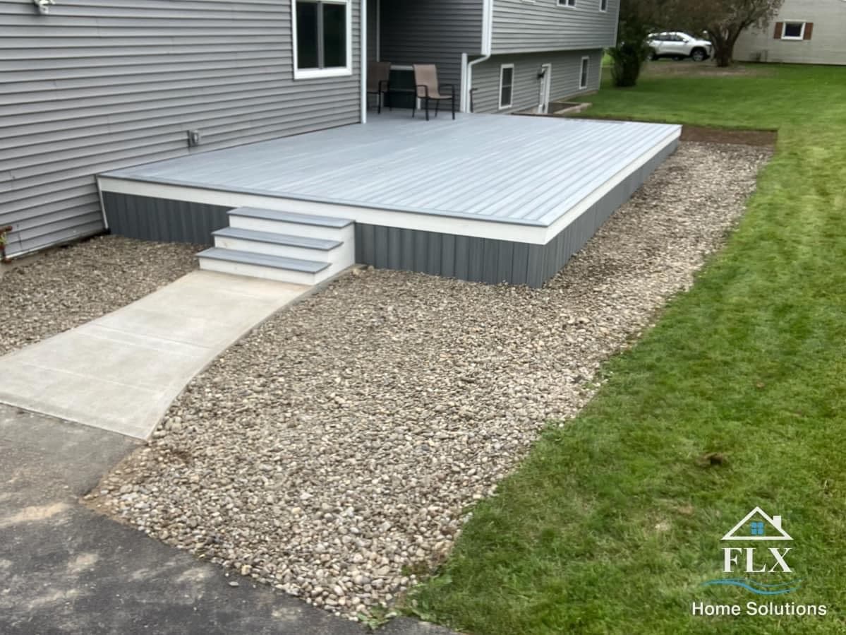 Gray composite deck with white trim and matching steps leading to gravel path