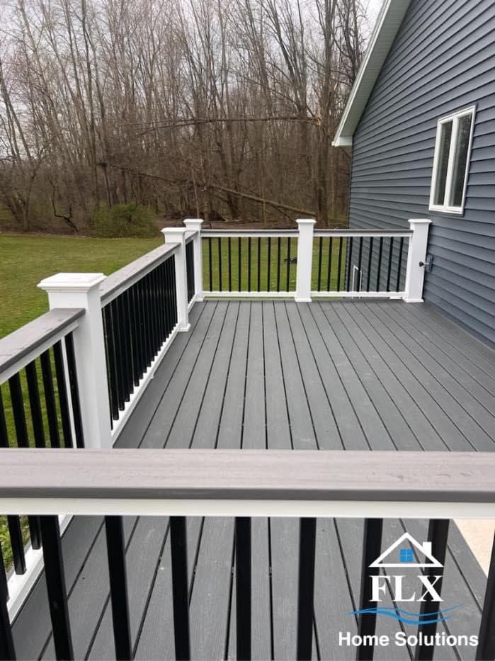 Gray composite deck with white posts and black metal balusters overlooking wooded backyard
