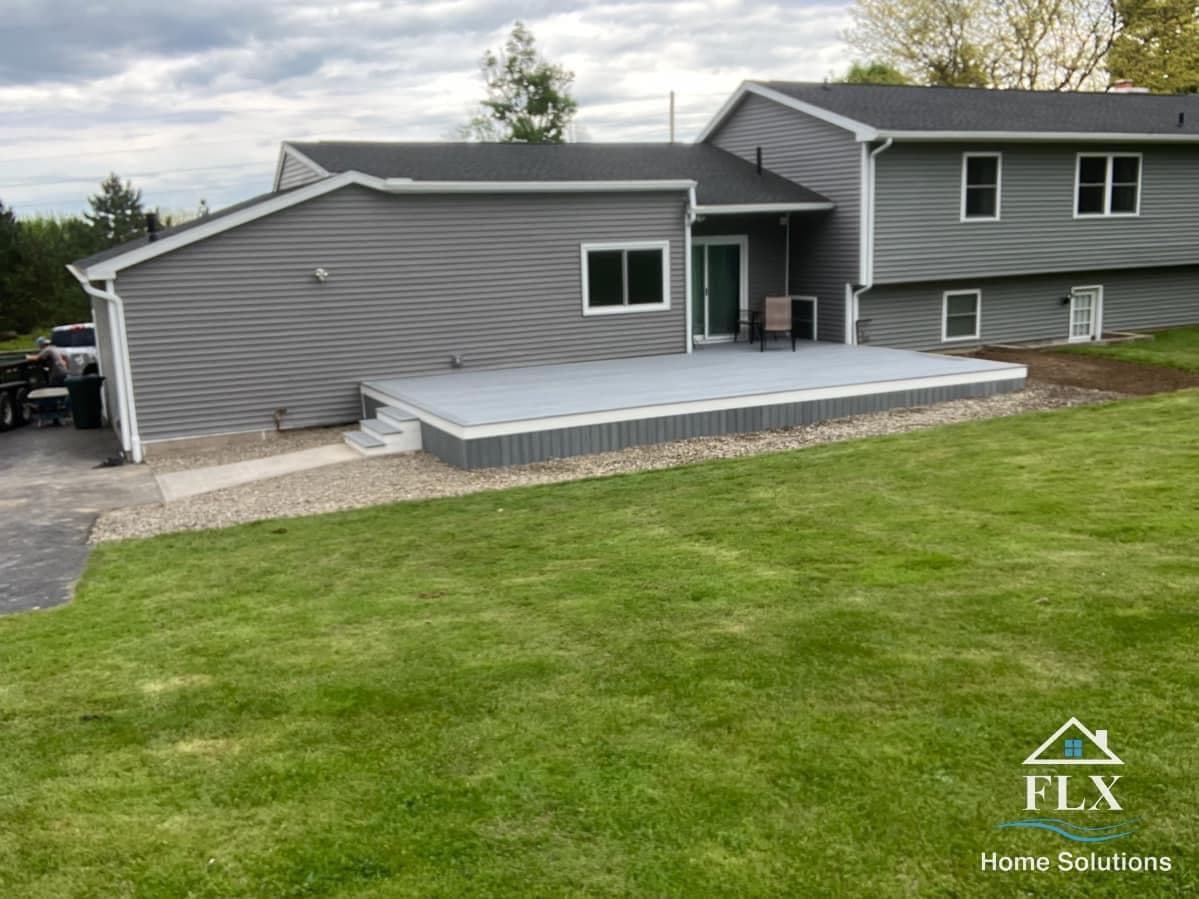 Gray house with elevated concrete deck and gravel border