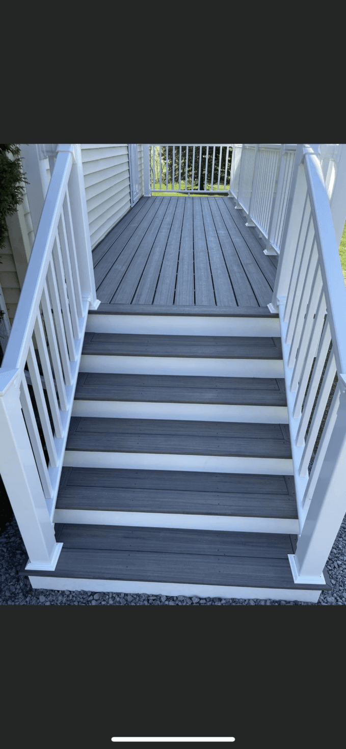 Outdoor deck stairs with gray treads, white risers, and white railings