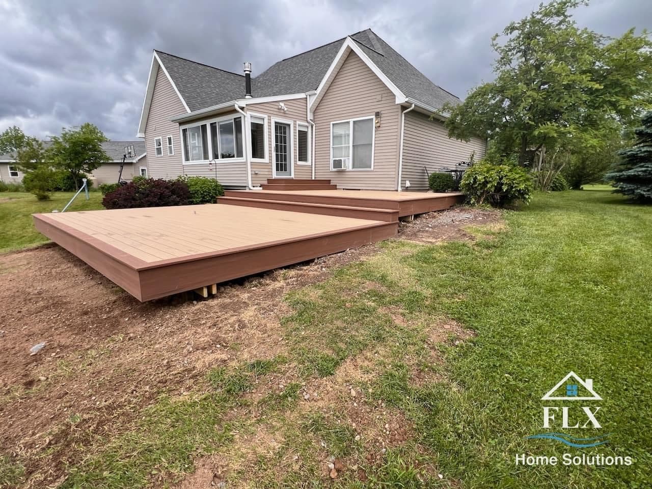 Two-tiered composite deck with steps extending from back of tan sided house
