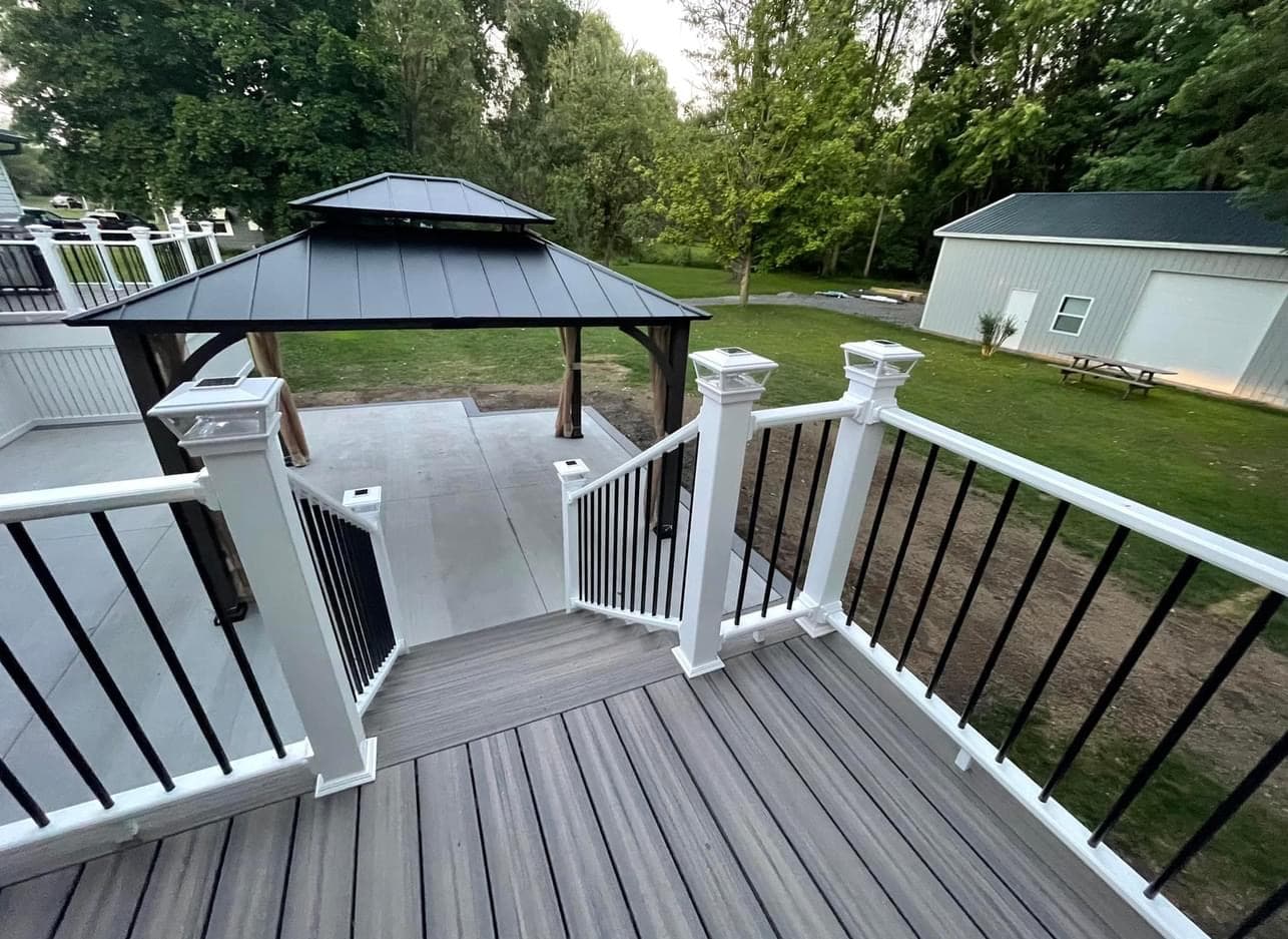 Multi-level composite deck with white railings, stairs, and dark gazebo