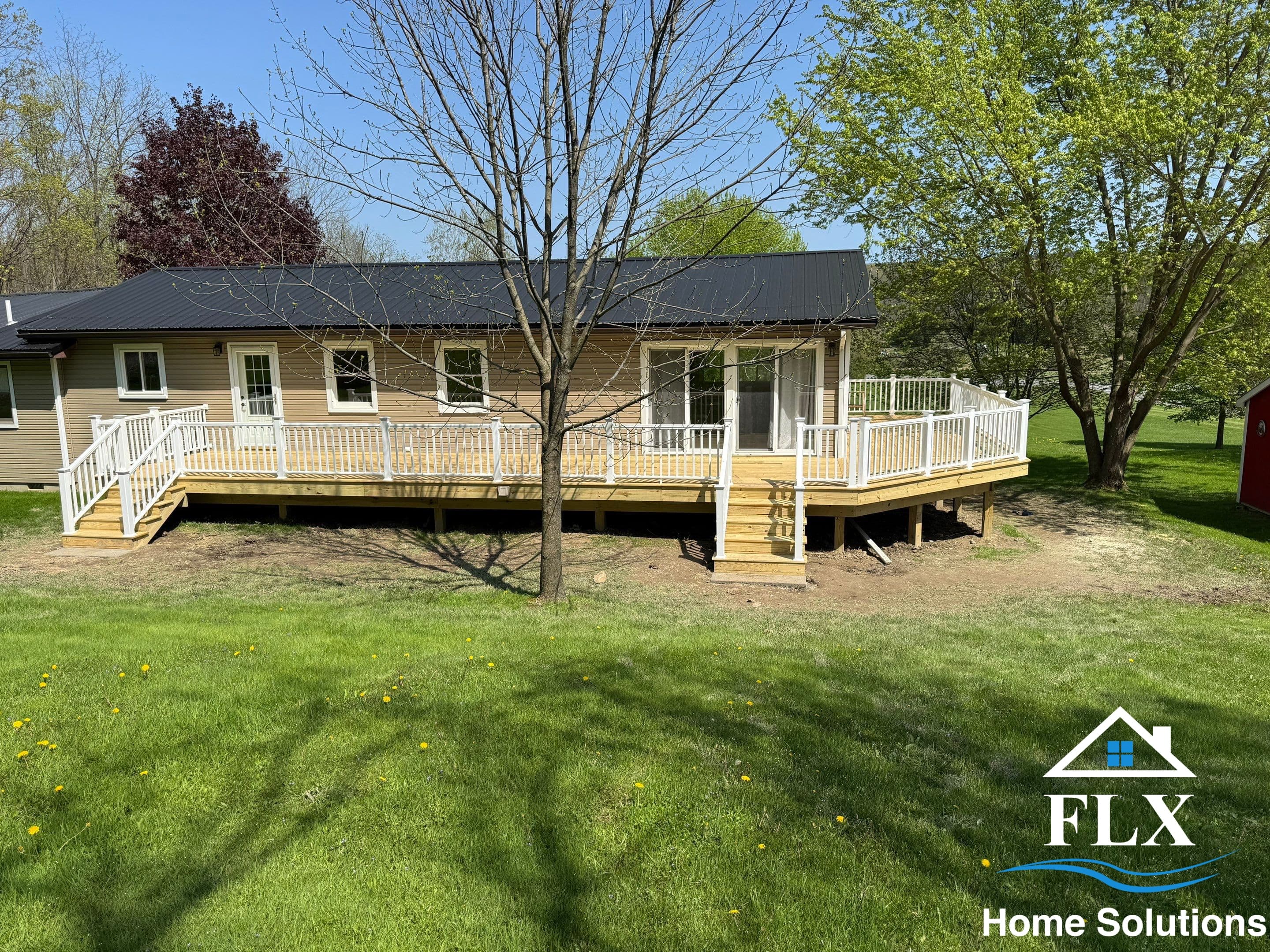 Tan ranch home with new wraparound wood deck and white railings