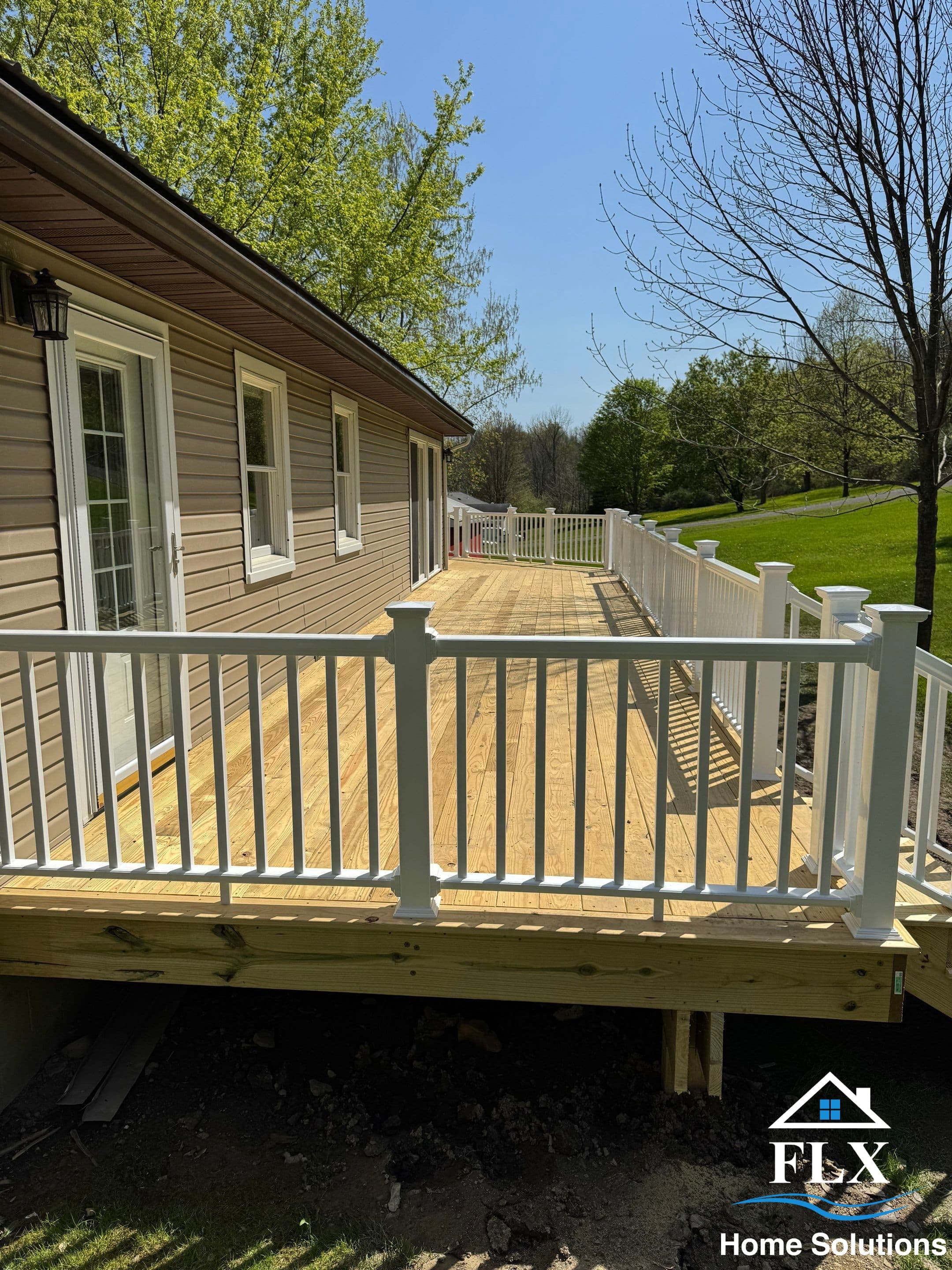 Newly constructed wooden deck with white railings overlooking green lawn