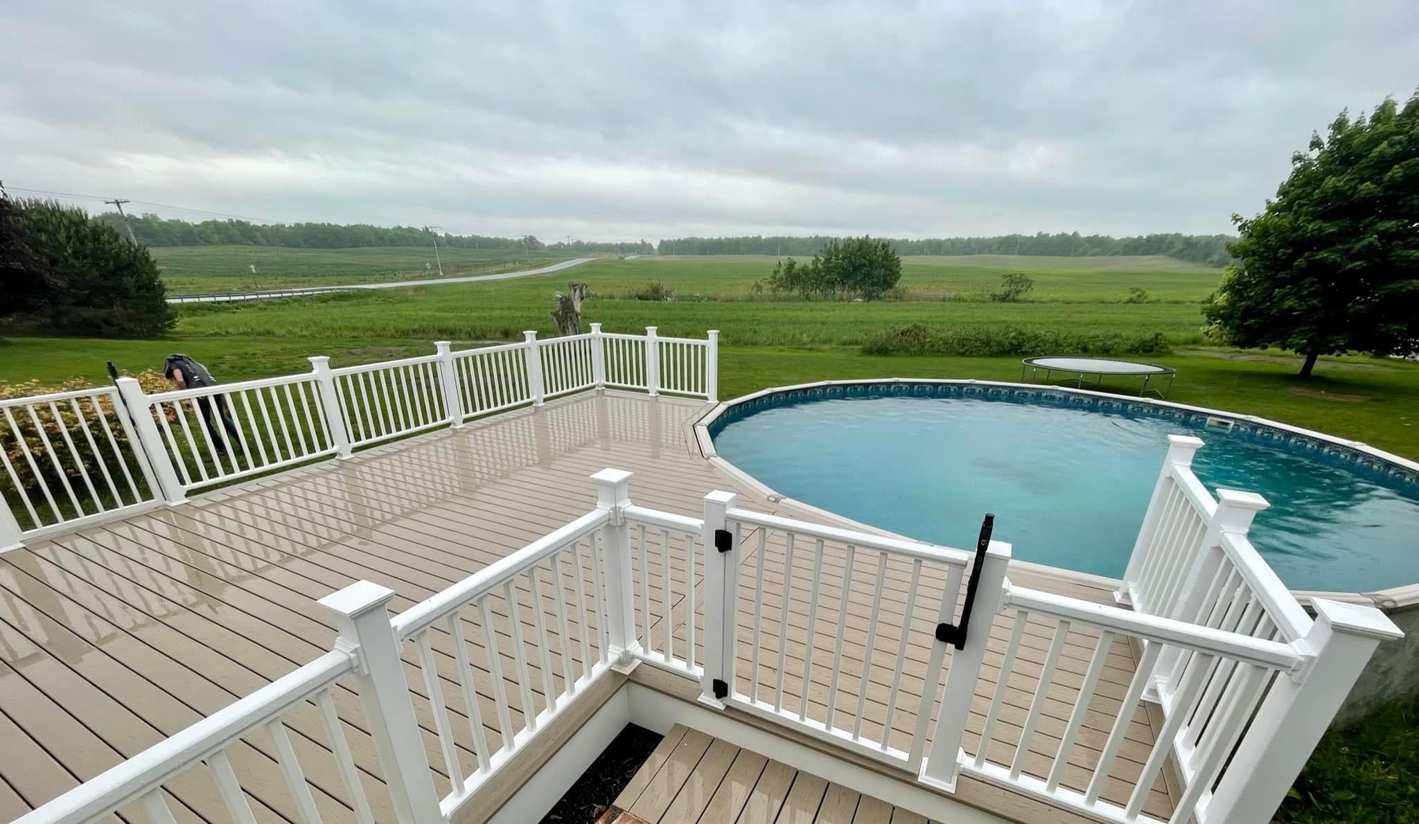 Custom composite deck with white railing overlooking above-ground pool and countryside