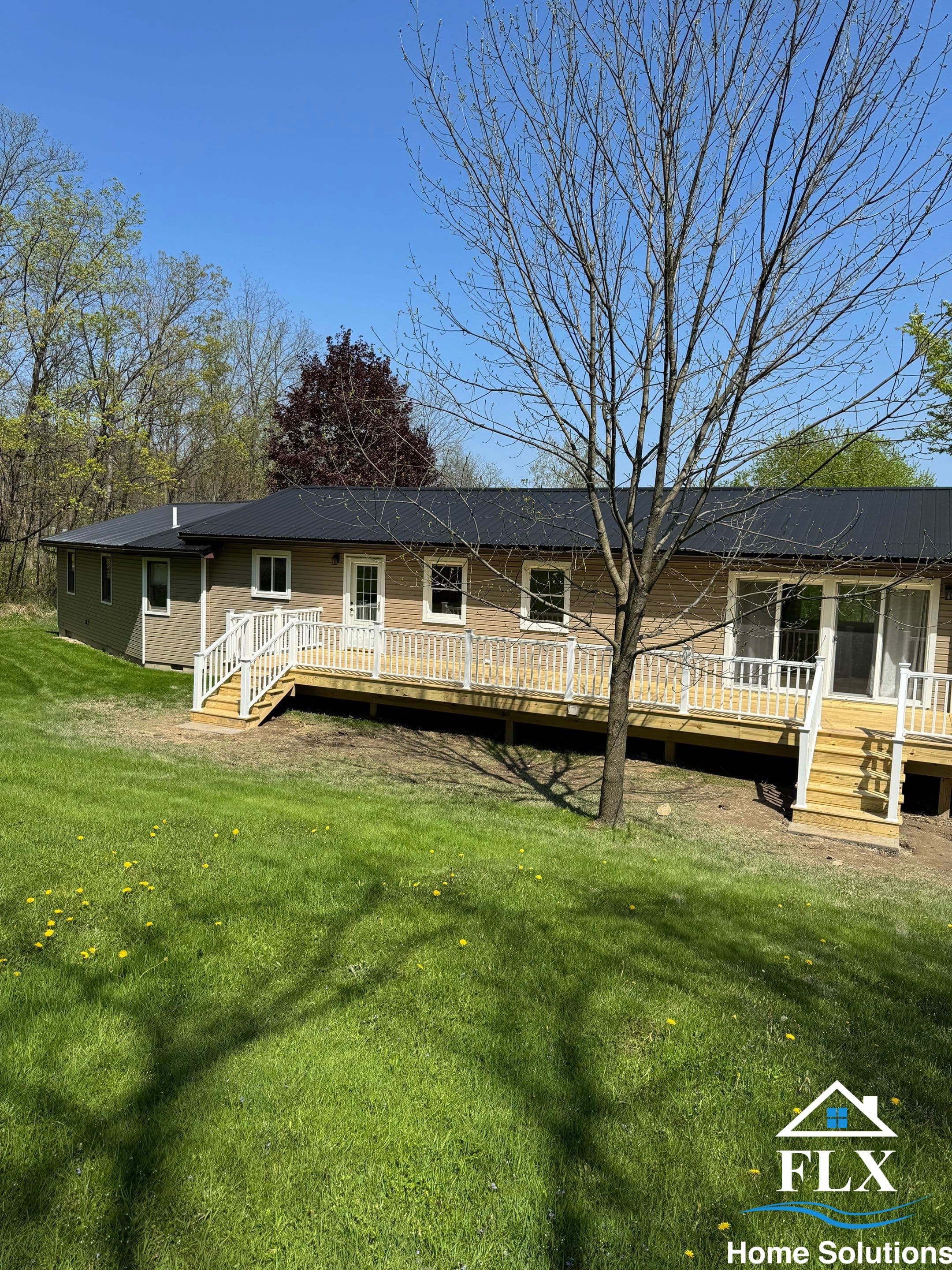 Single-story ranch home with new wraparound wooden deck and white railings