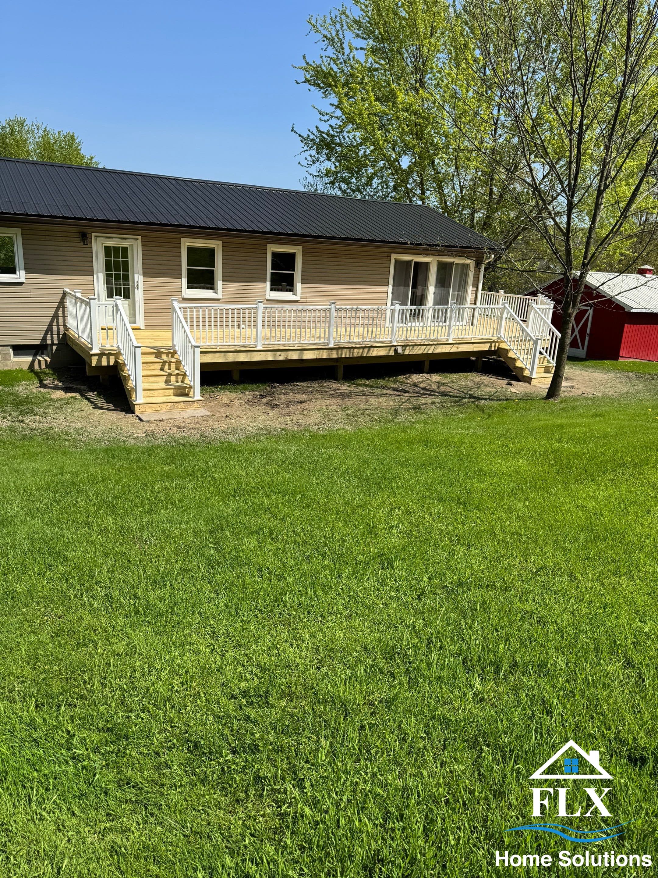 Single-story tan house with new white-railed deck and metal roof