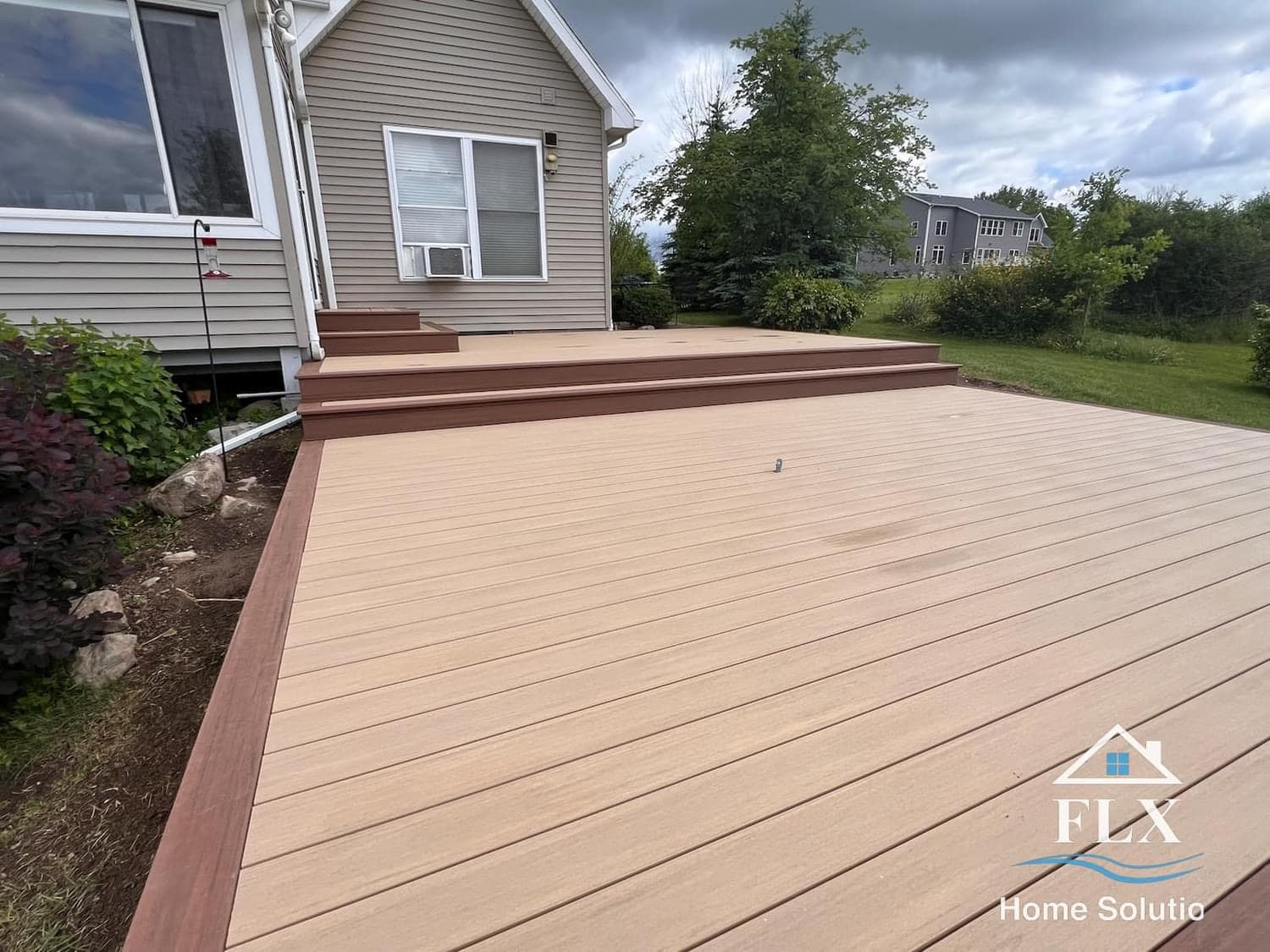 Two-tone composite deck with brown trim and beige decking and integrated steps