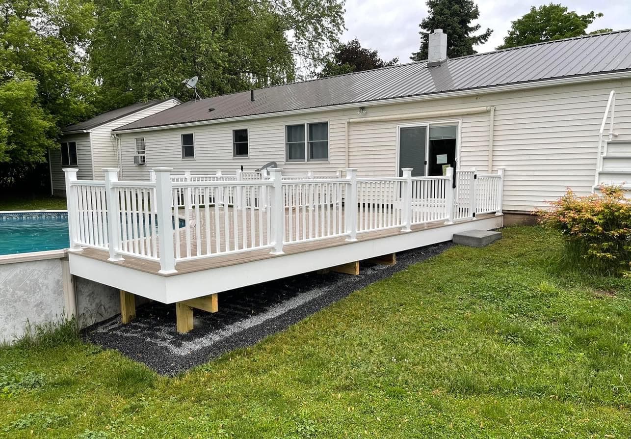 White composite deck with white railings next to above-ground pool