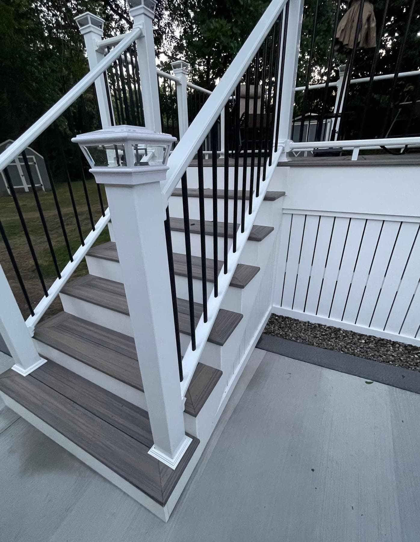 White composite deck stairs with gray treads and black metal railing