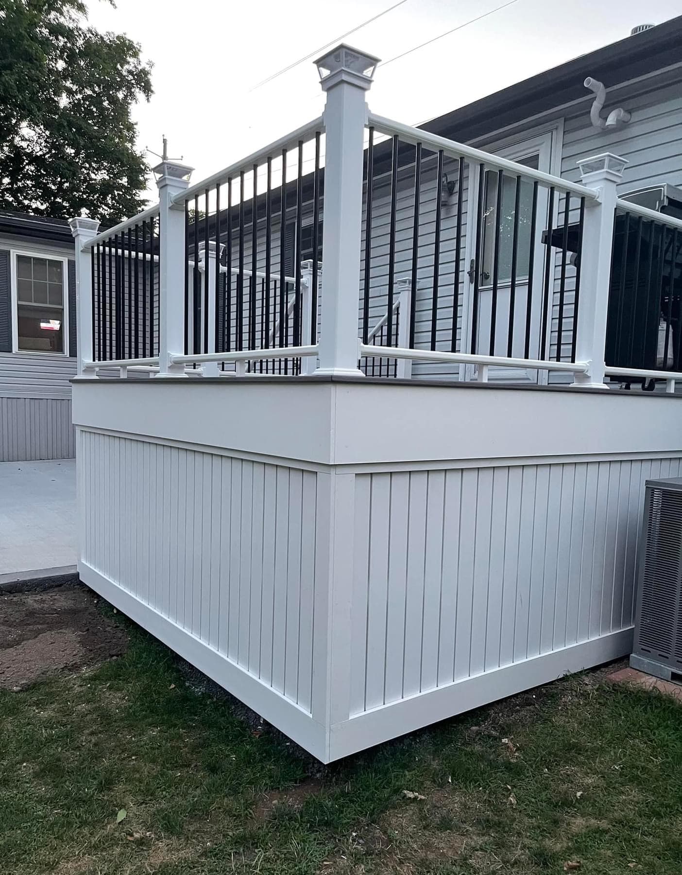 White deck with black metal railing and vertical skirting