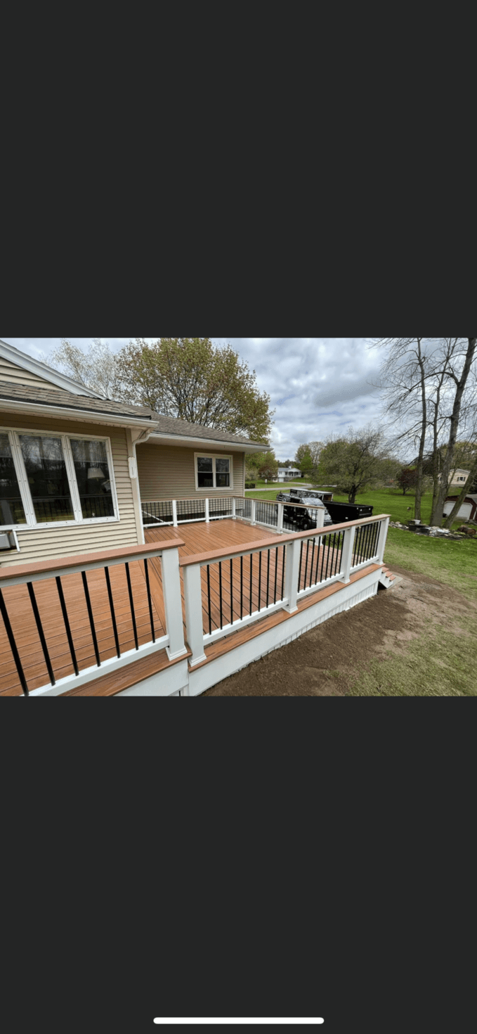 Custom wood deck with white railings and stairs overlooking backyard