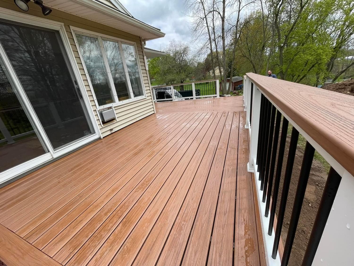 Composite wood-grain deck with white and black railing overlooking yard