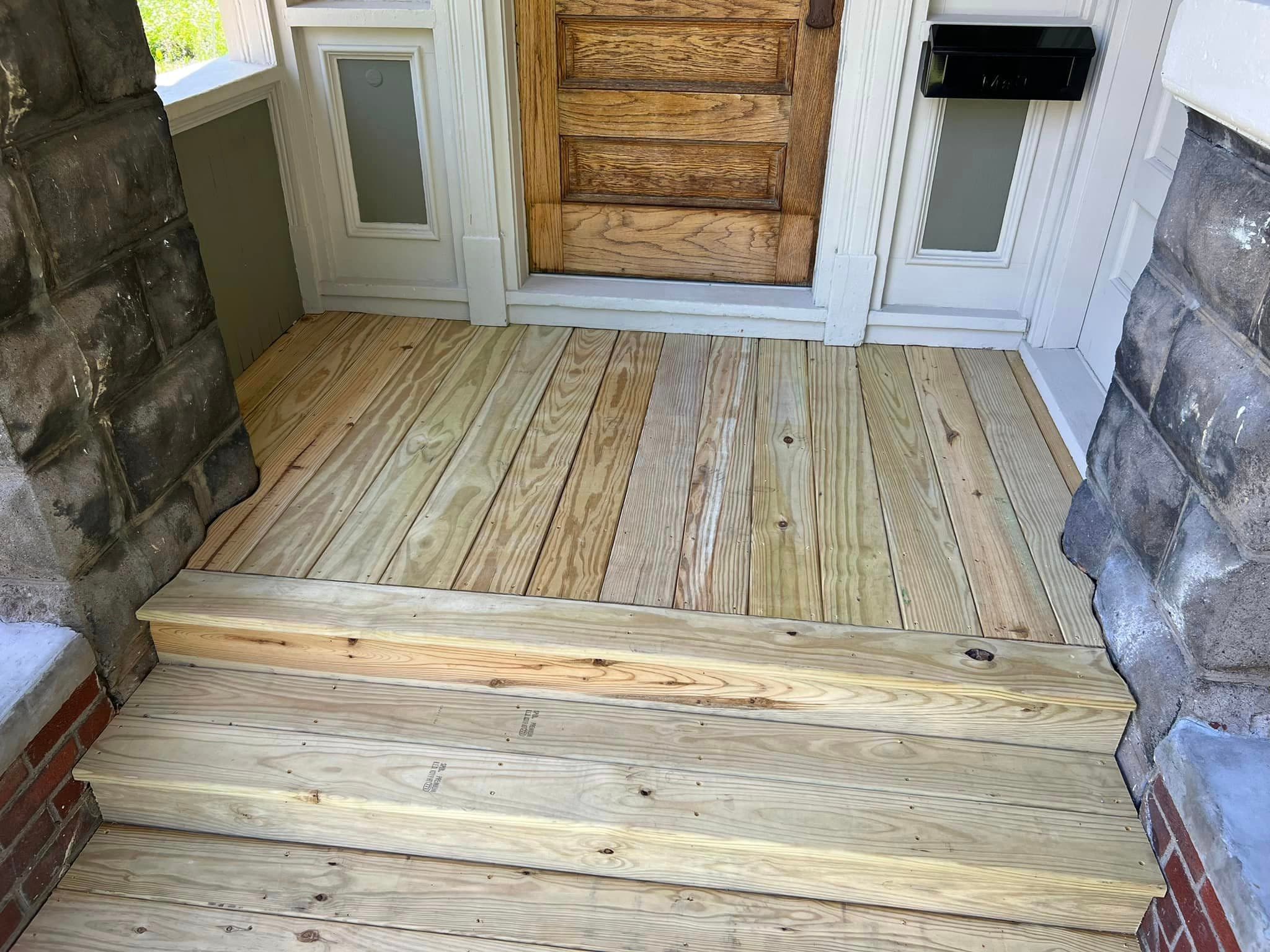 New wooden deck and steps leading to front door with stone walls
