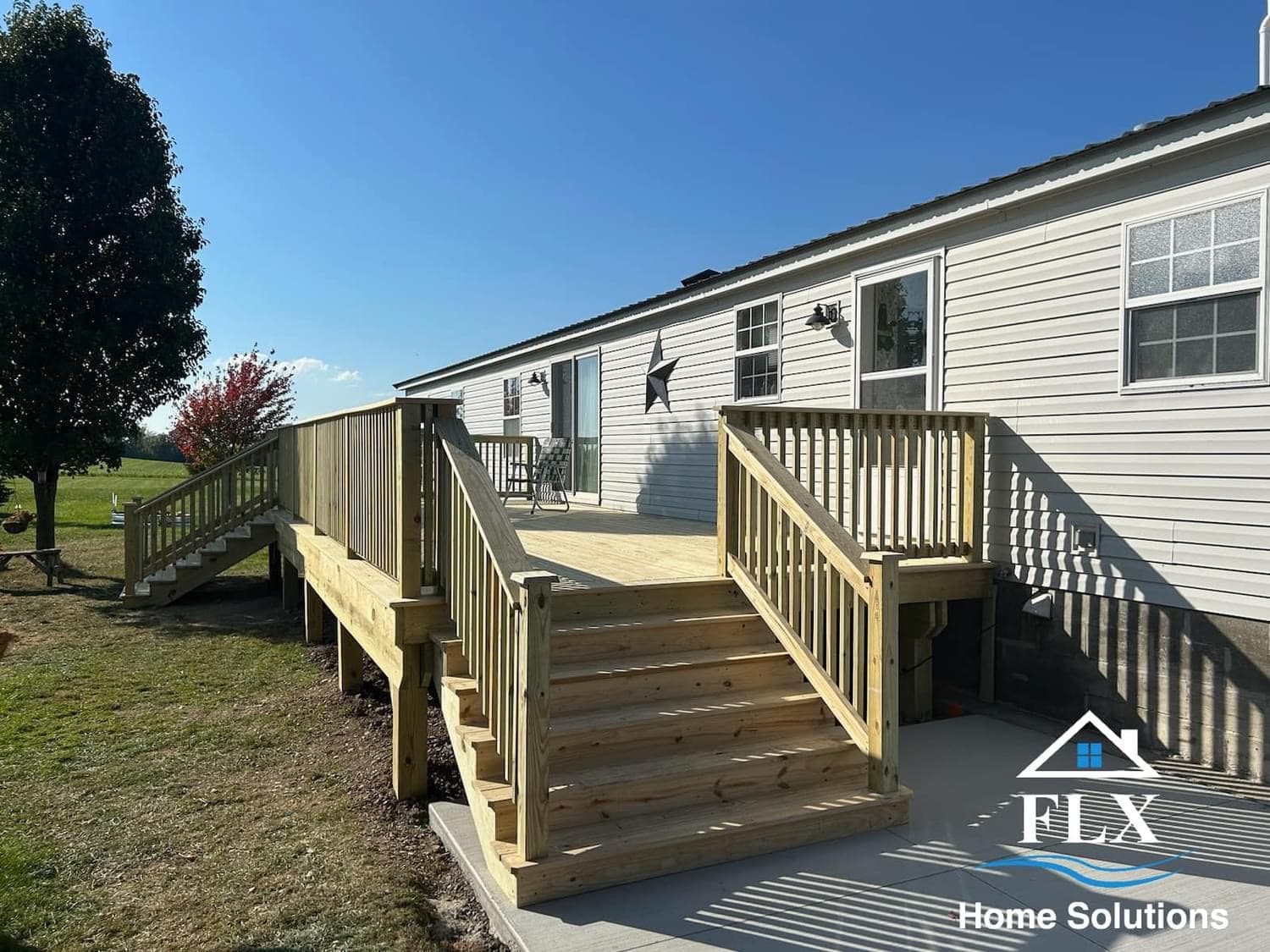 New wooden deck with railings and stairs attached to white mobile home