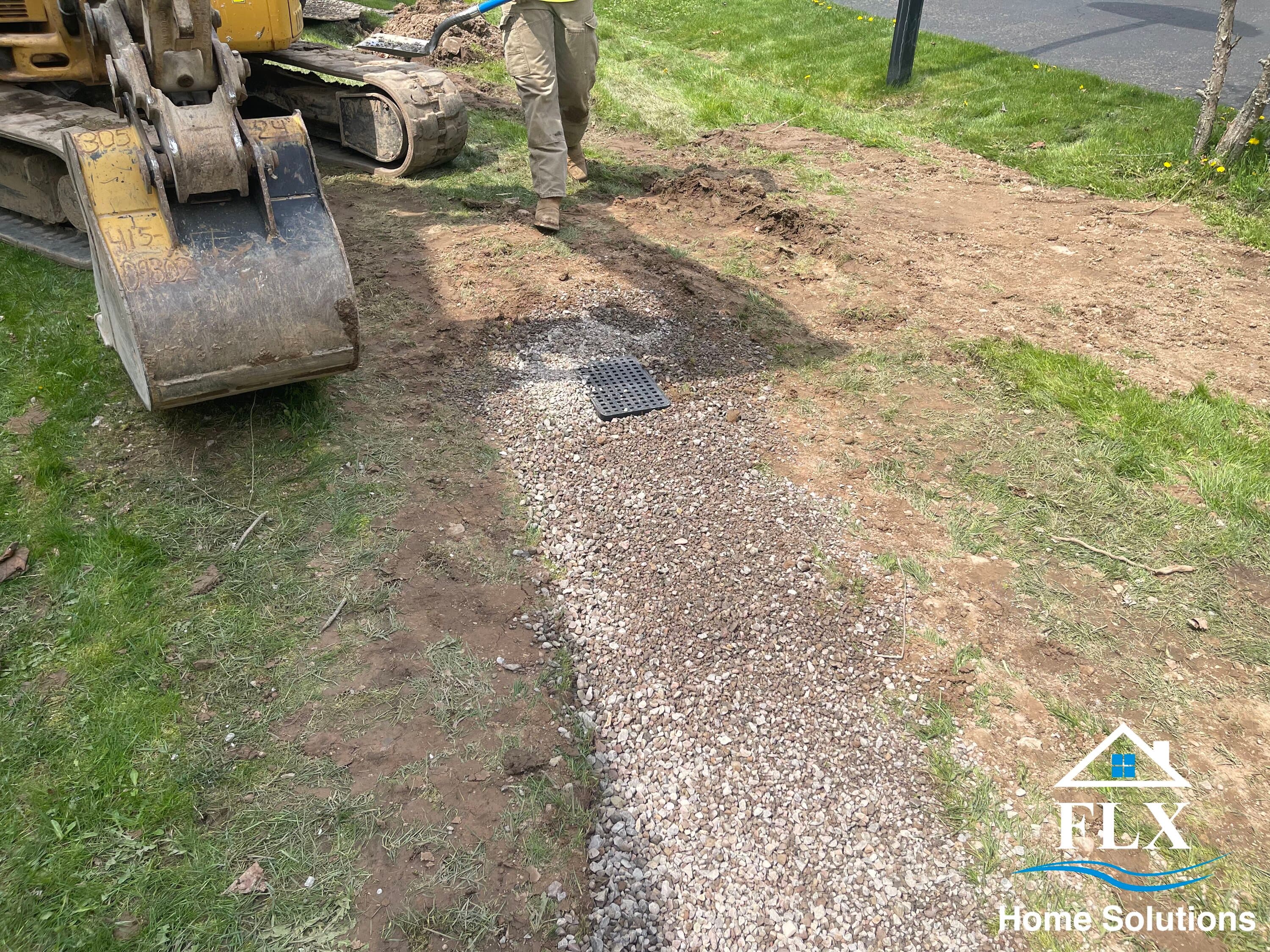 Gravel-filled trench with drainage grate installed during excavation work
