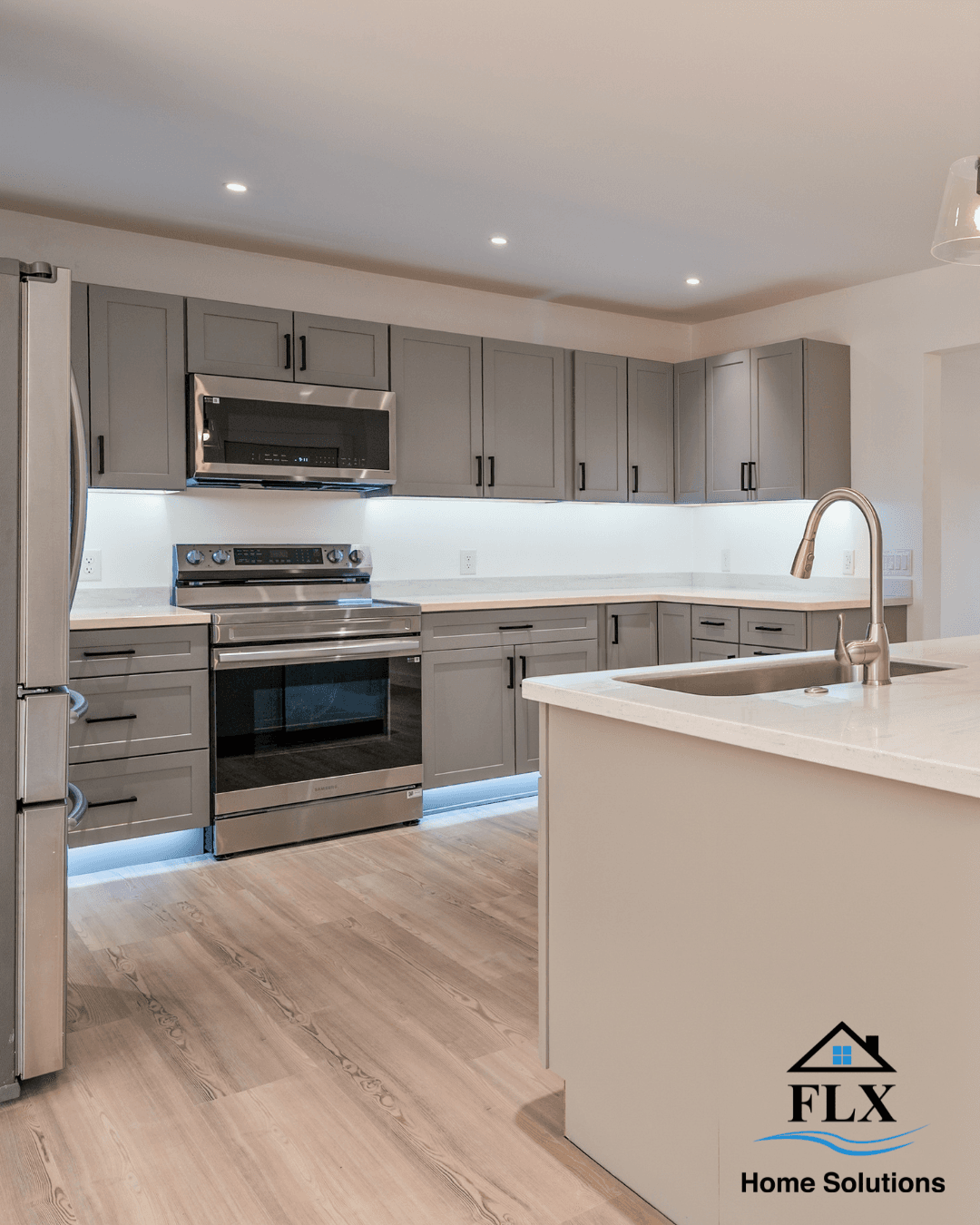 Modern kitchen with gray cabinets, white countertops, and stainless steel appliances