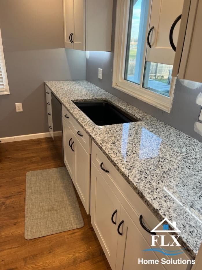 Modern kitchen with white cabinets, speckled granite countertops, and black sink