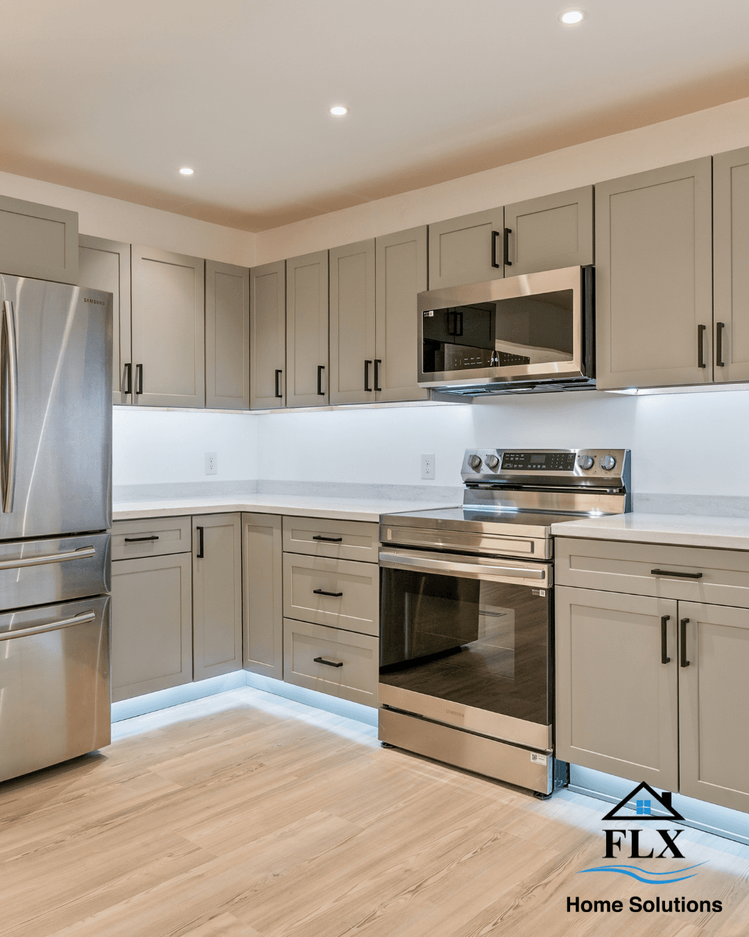 Modern kitchen with light gray cabinets, stainless appliances, and white countertops
