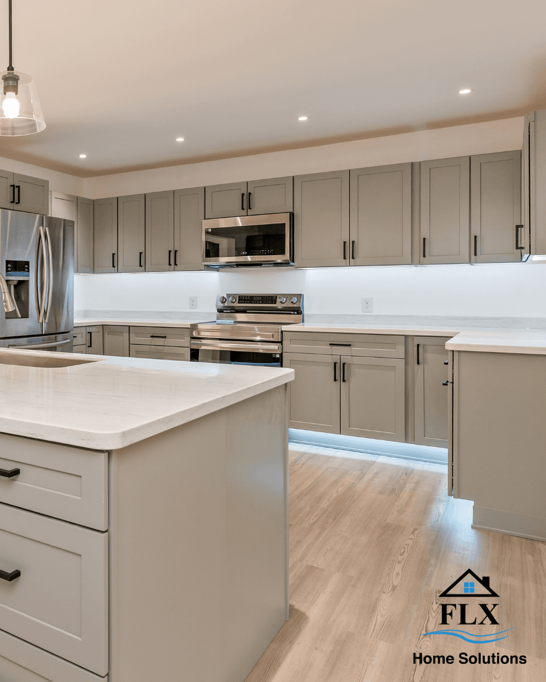 Modern kitchen with gray shaker cabinets, white countertops, and blue LED toe kick lighting