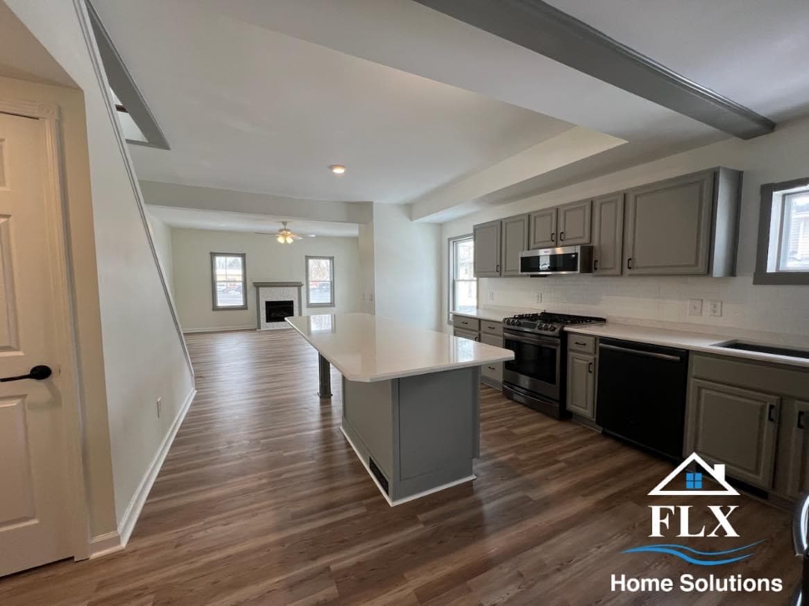 Open concept kitchen with gray cabinets, white countertops, and hardwood floors