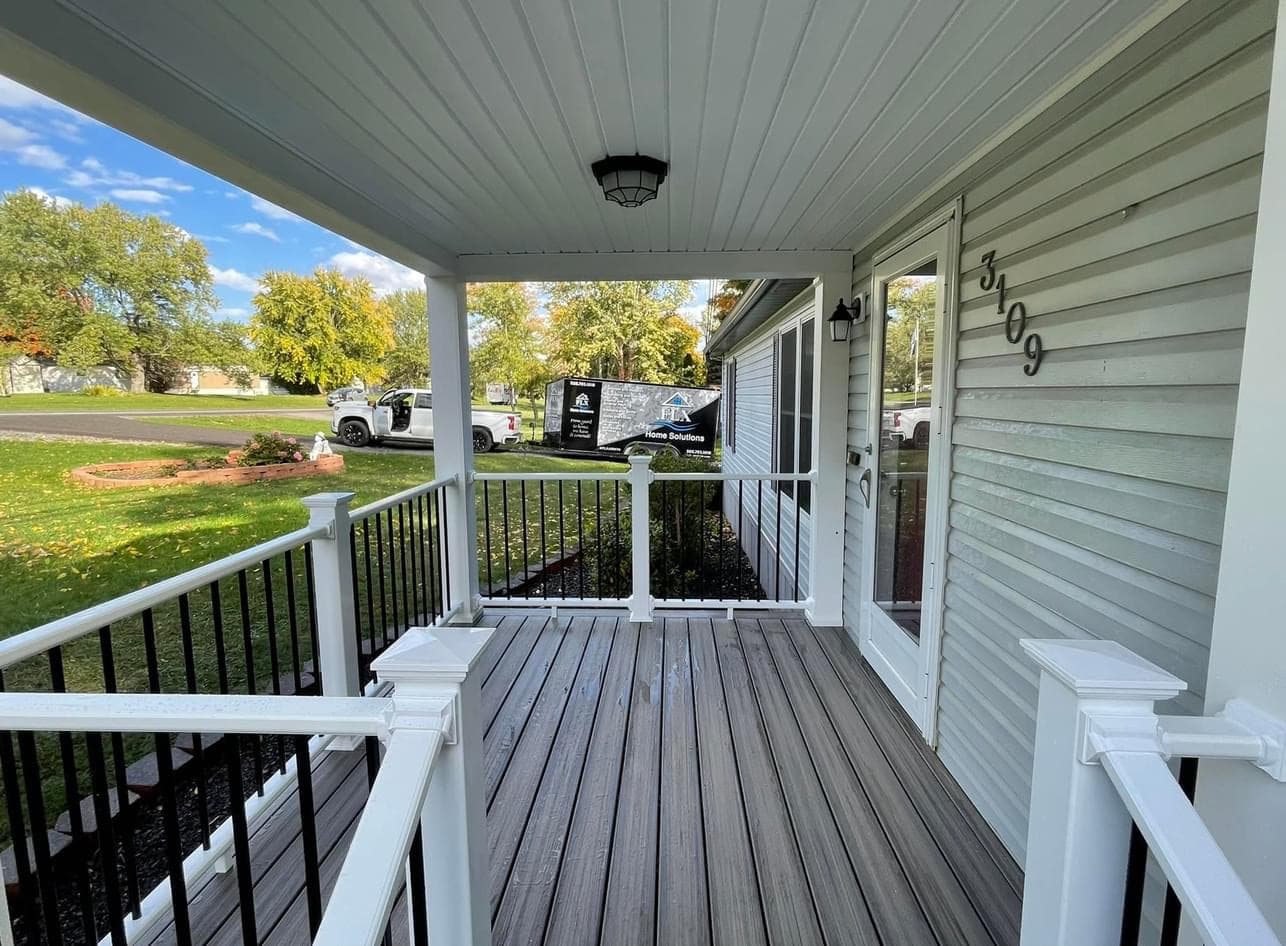 Covered front porch with gray composite decking and white railings at house 309