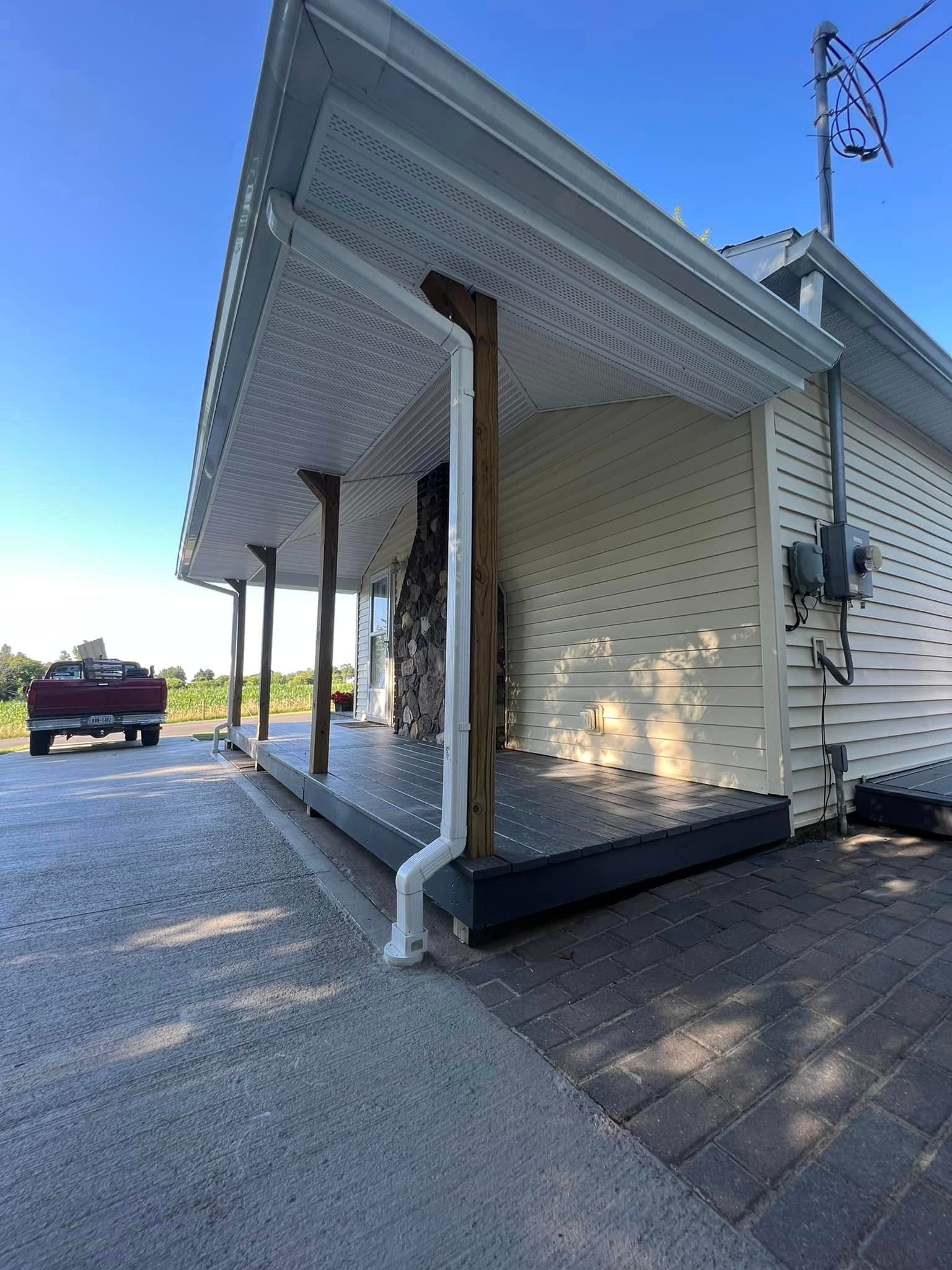 Covered front porch with white vinyl siding and dark decking
