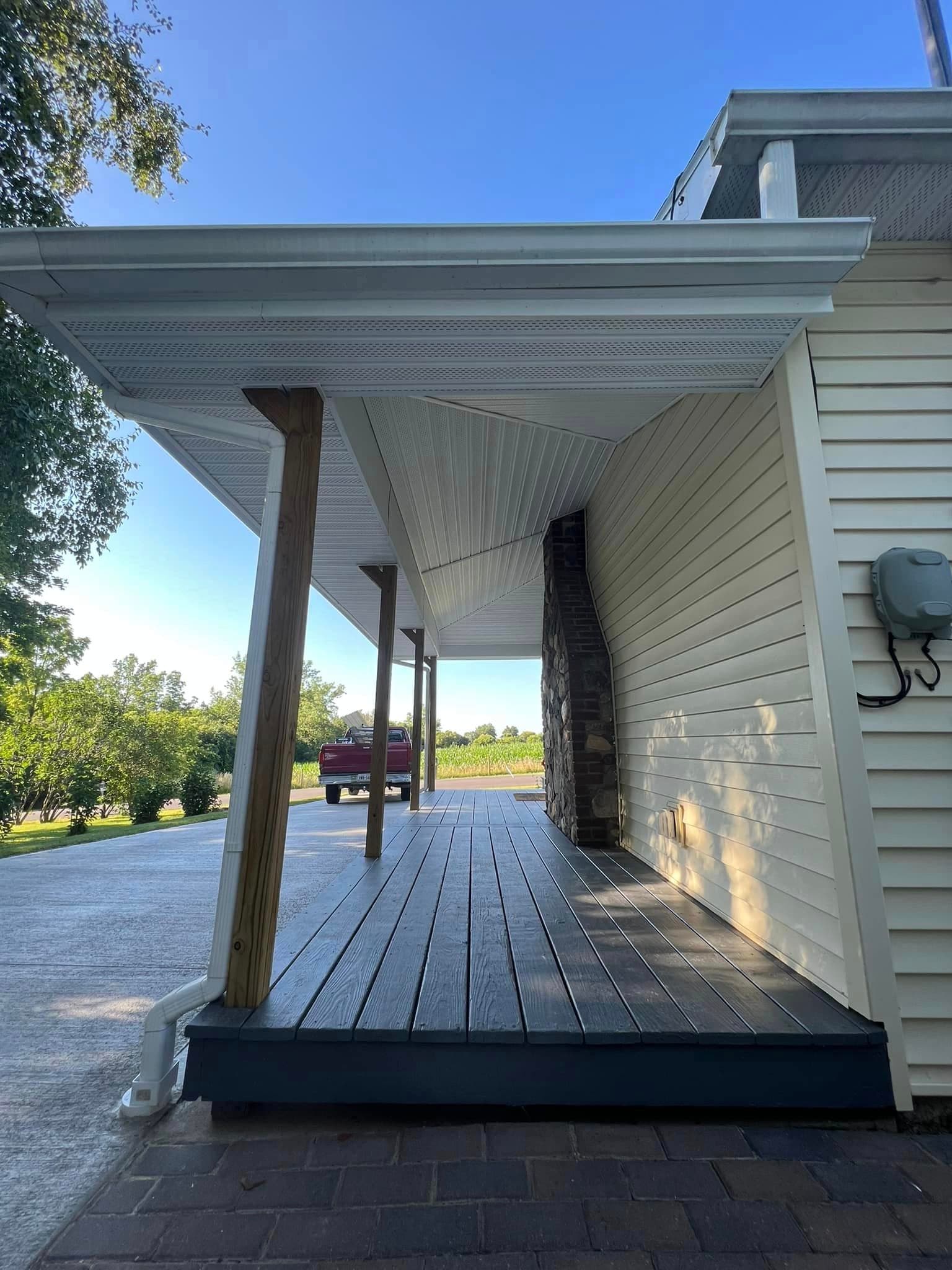 Covered porch with dark composite decking and white vinyl siding