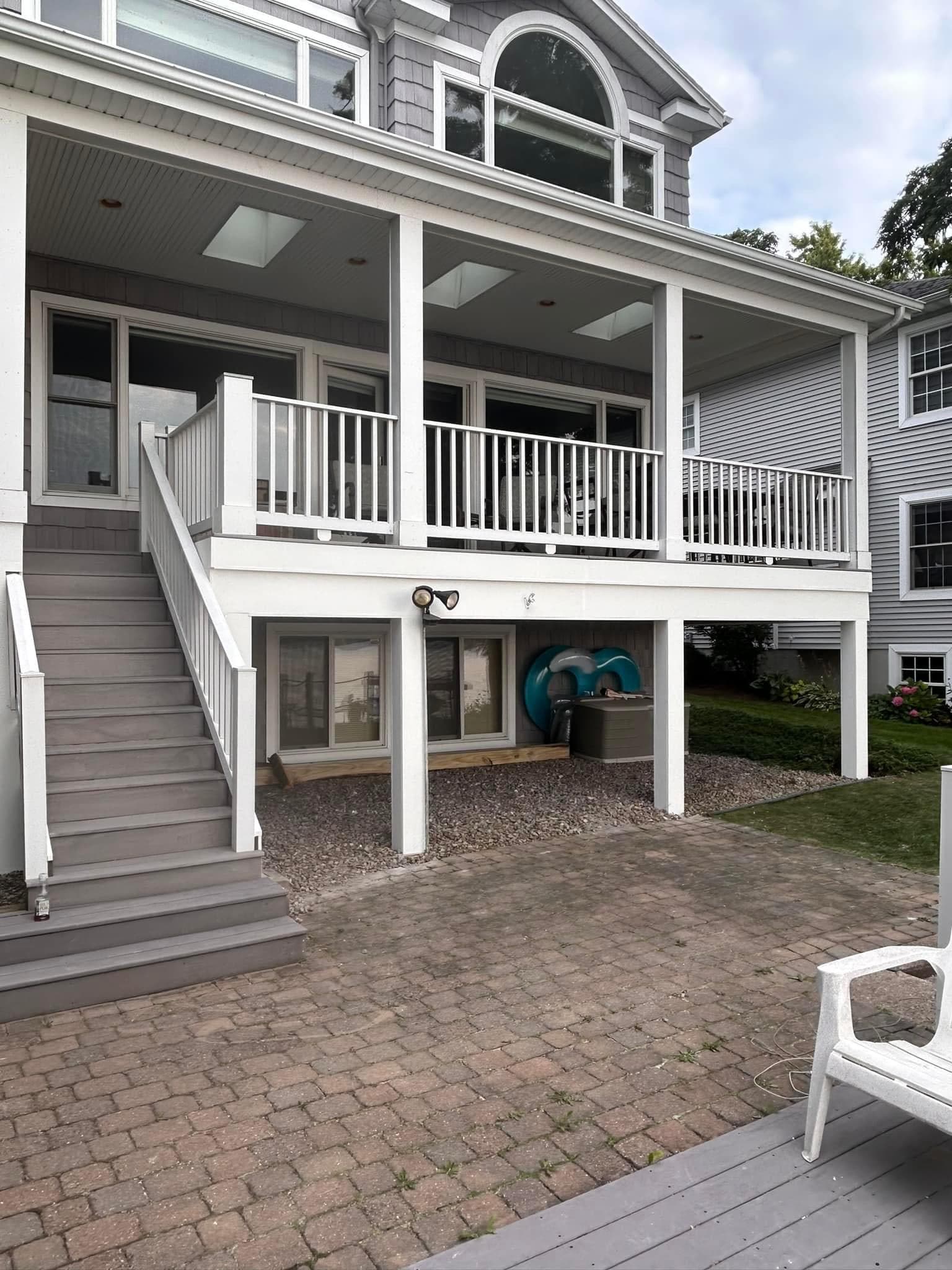 Two-story covered porch with white railings and gravel patio underneath